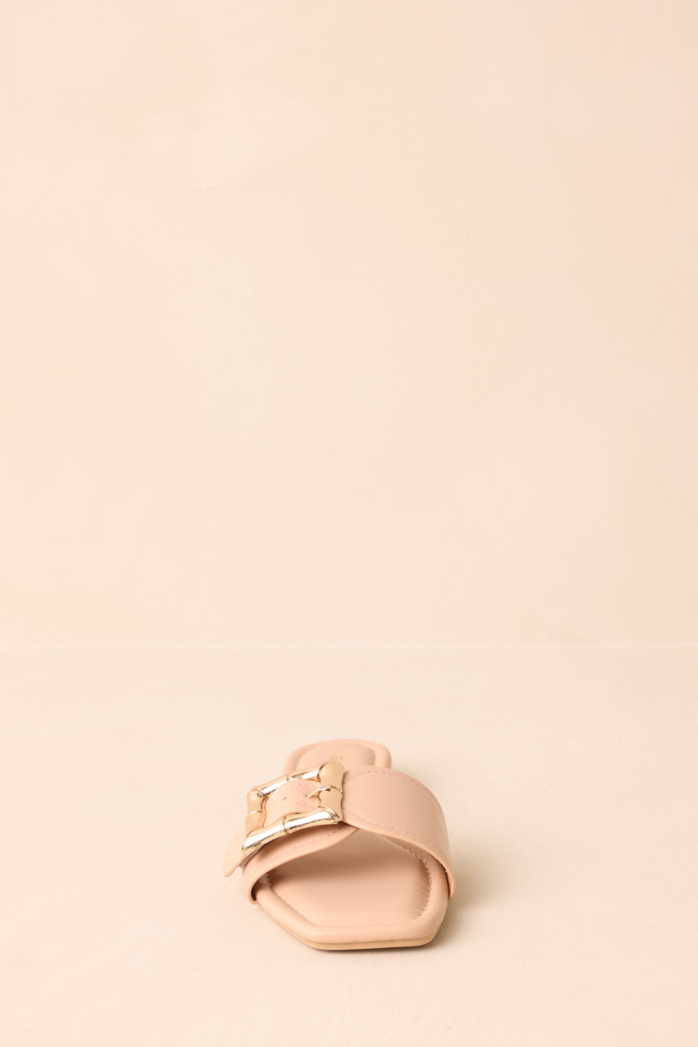 Front-facing view of beige sandals highlighting buckle detail.
