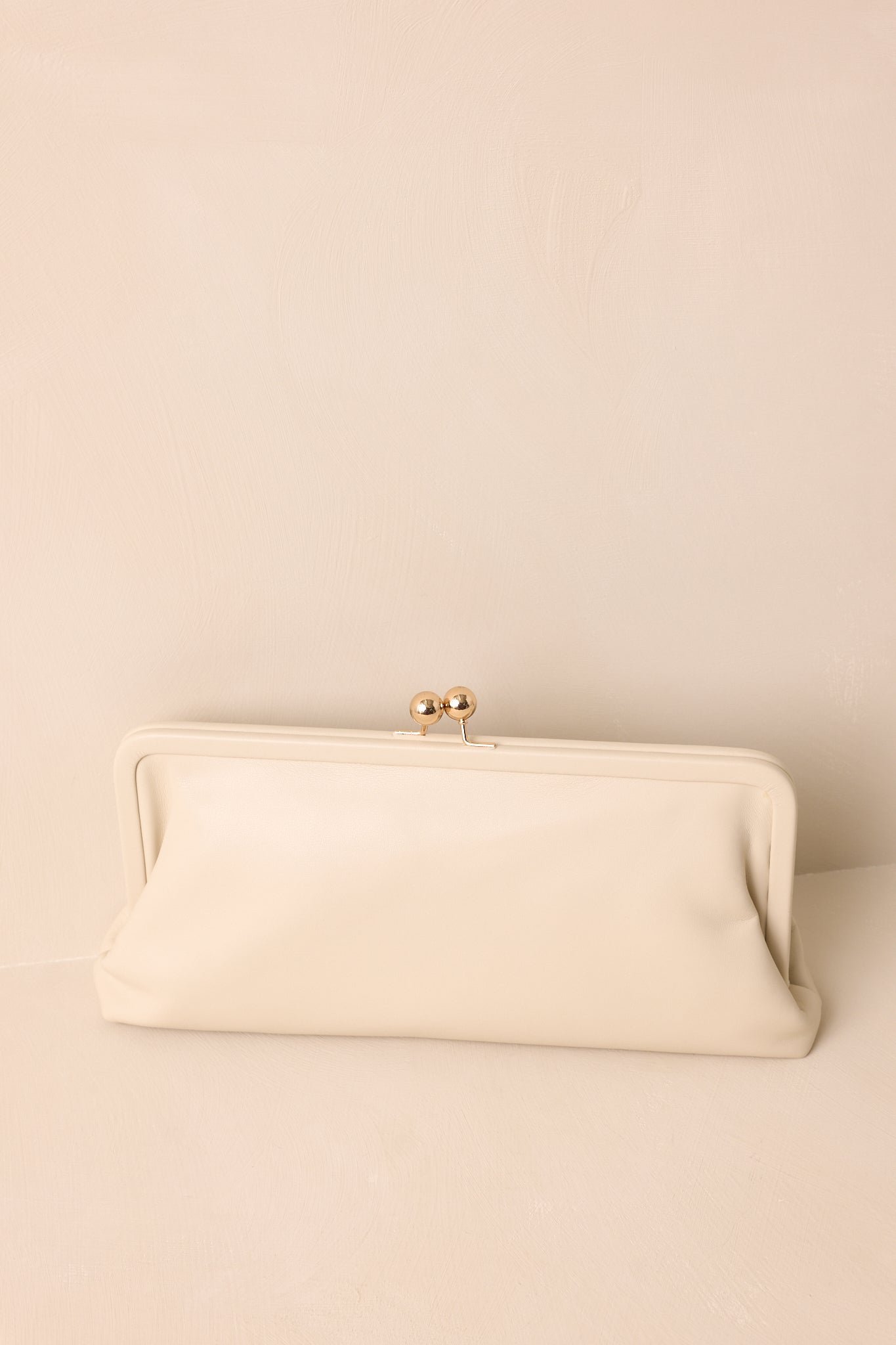Front view of the ivory clutch showing its rectangular silhouette and gold kiss-lock closure.