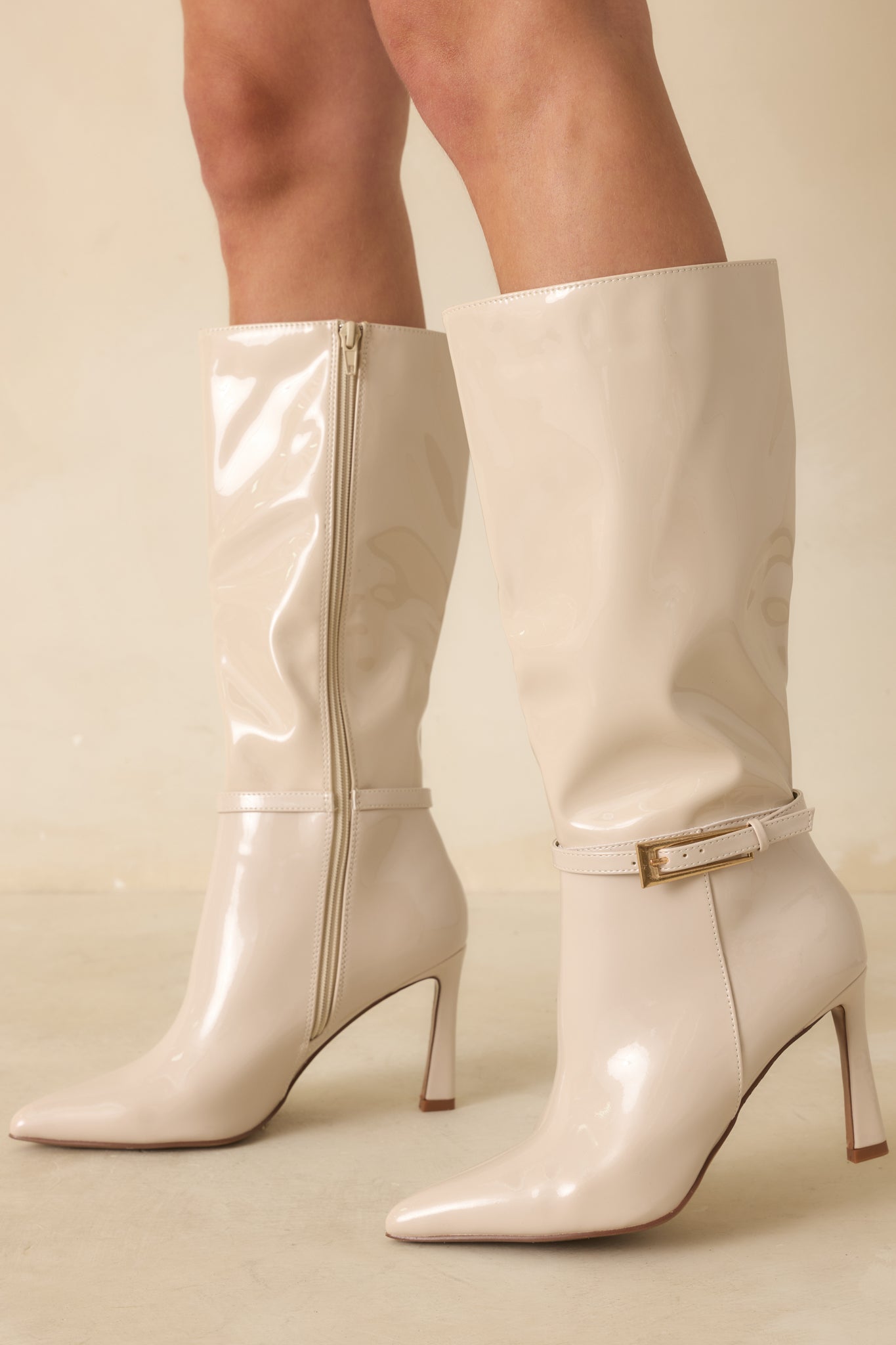 Front view of ivory patent faux leather boots with pointed toe, stiletto heel, and mid-calf height.