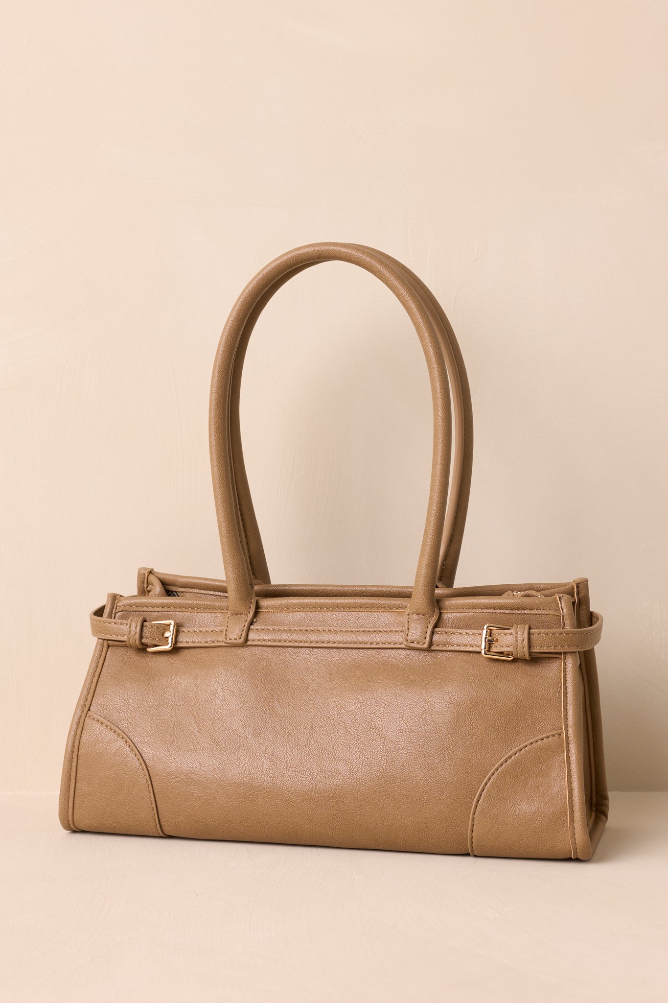 Front view of the light mocha handbag showing its rectangular silhouette, rolled double top handles, and belted side detailing.