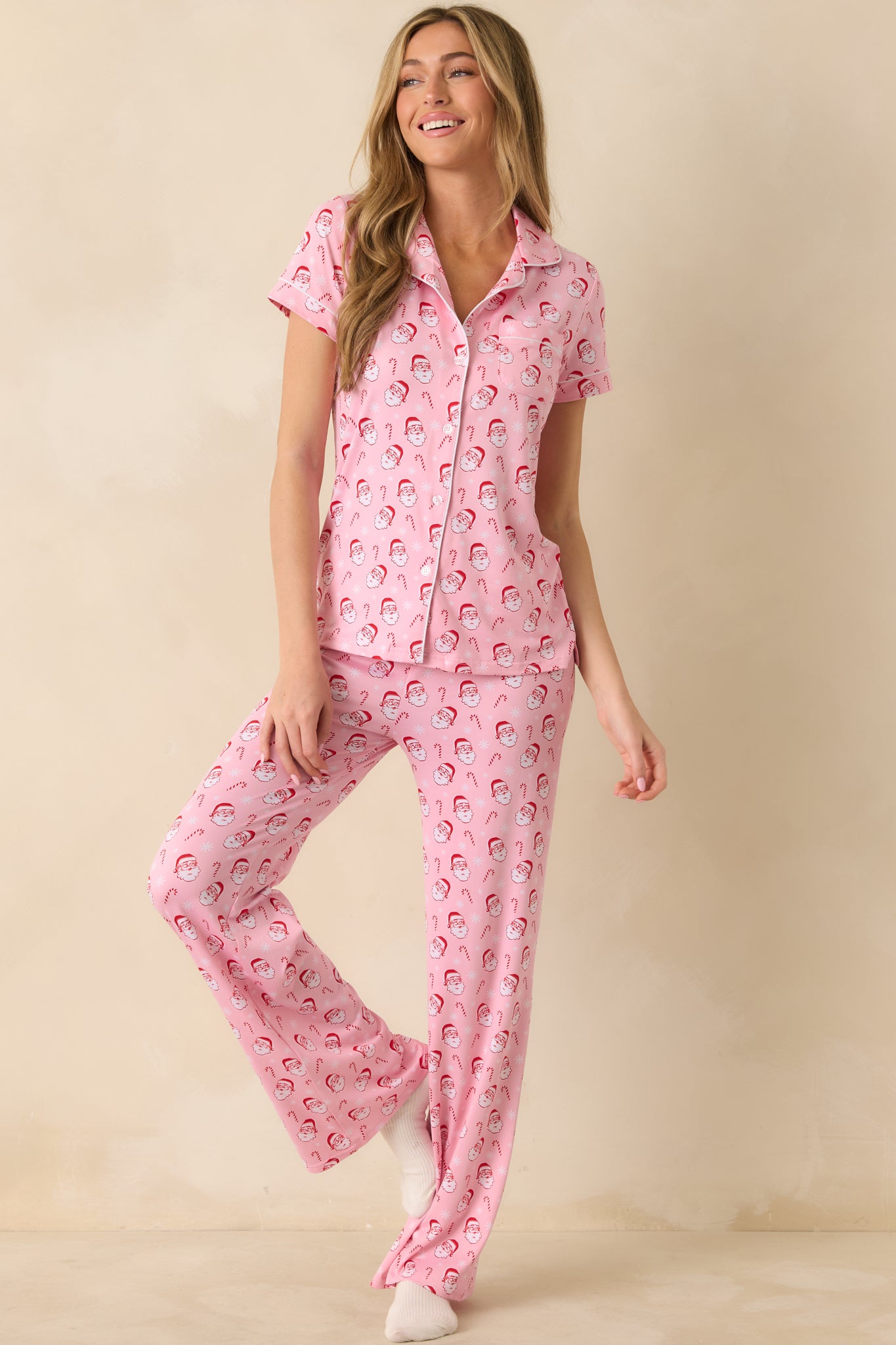 Front view of the light pink pajama pants featuring an allover Santa and candy cane print with a relaxed full-length silhouette.