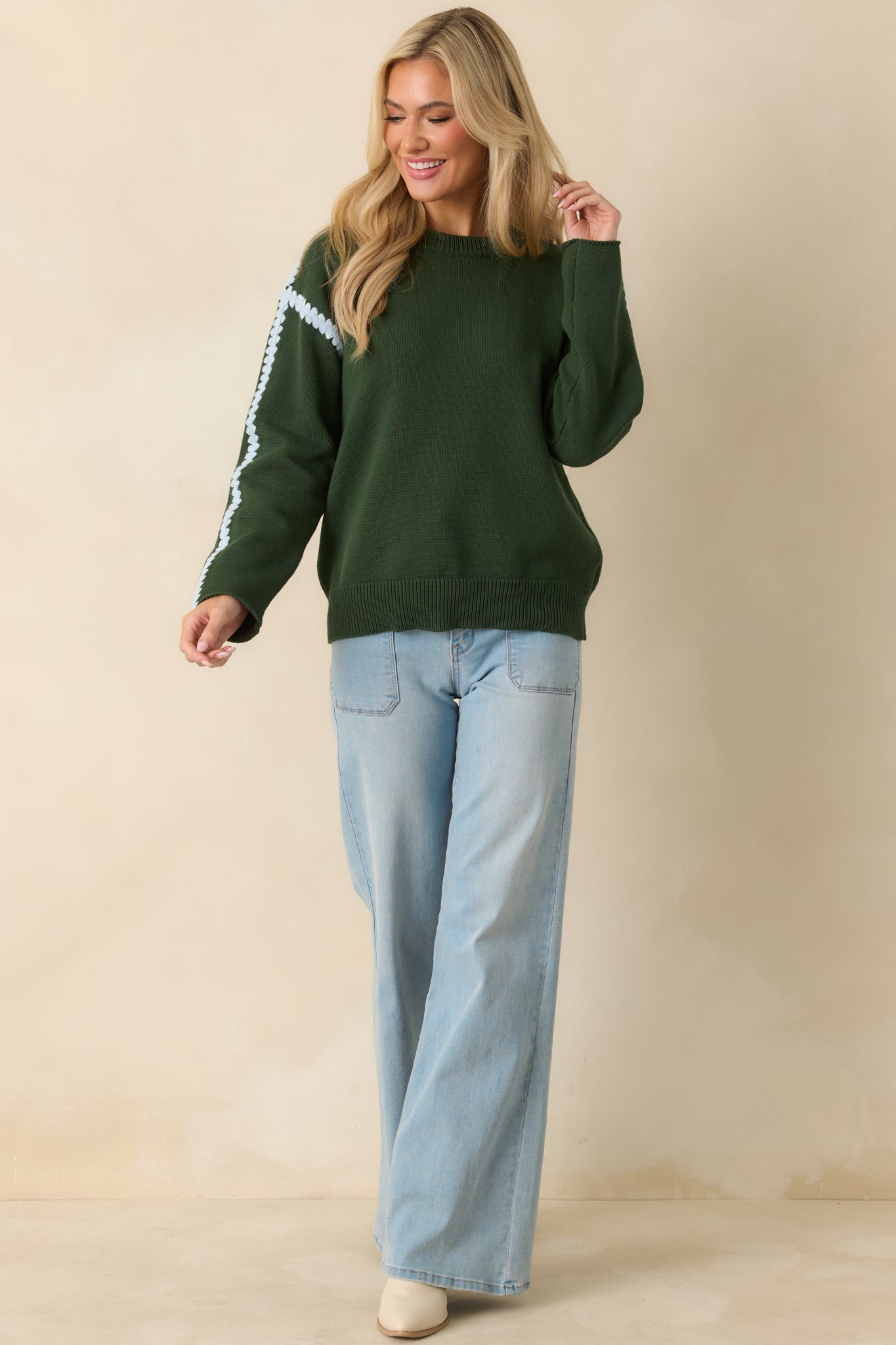 Front-facing moss green sweater highlighting the contrast blue crochet trim along the shoulders.