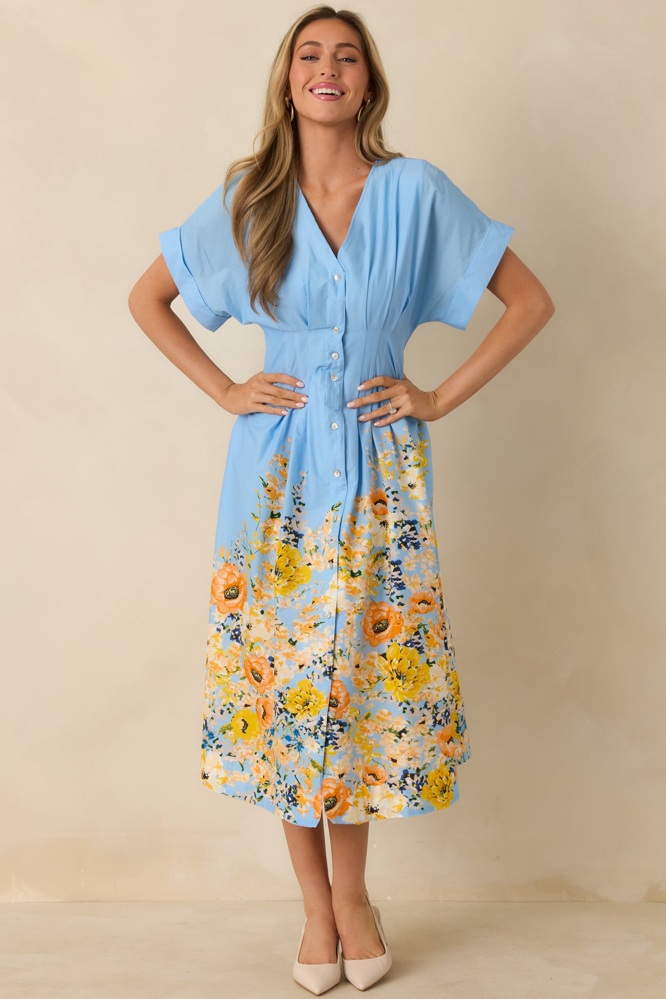 Front view of blue midi dress featuring multicolor floral border hem, flutter sleeves, and a flattering waist seam.