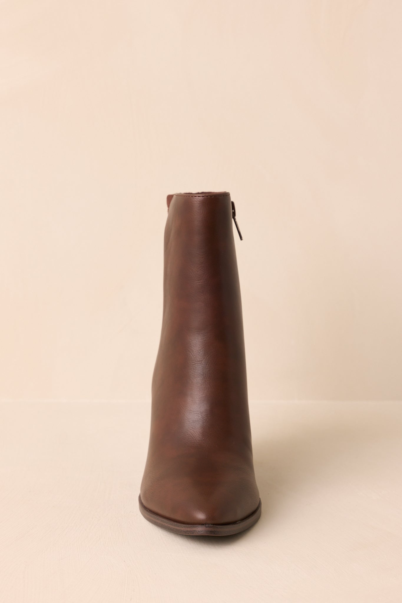 Front view of the brown ankle boots emphasizing the elongated pointed toe and smooth finish.