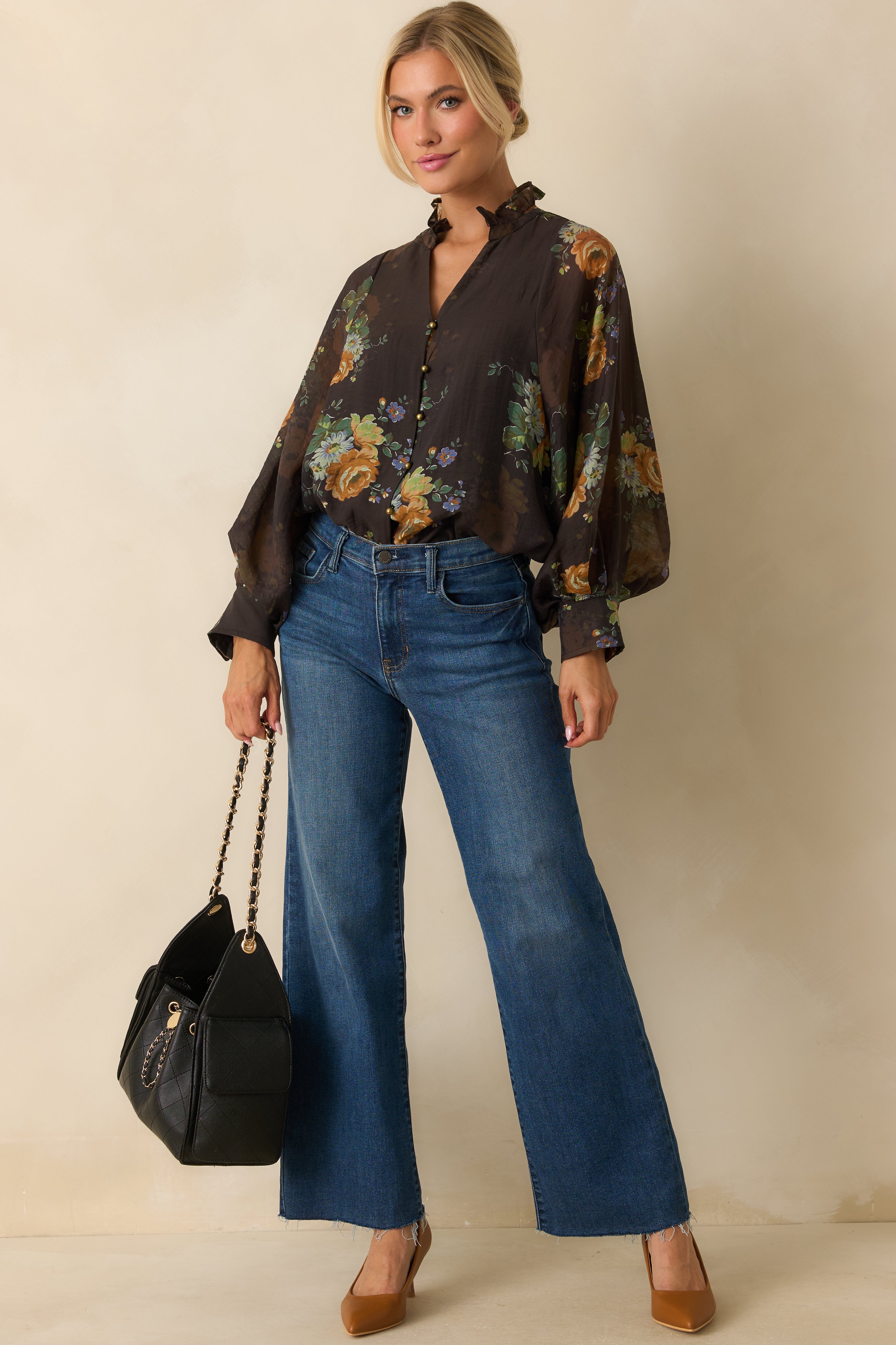 Front view of brown floral blouse with buttoned cuffs and ruffle detailing at the neckline.
