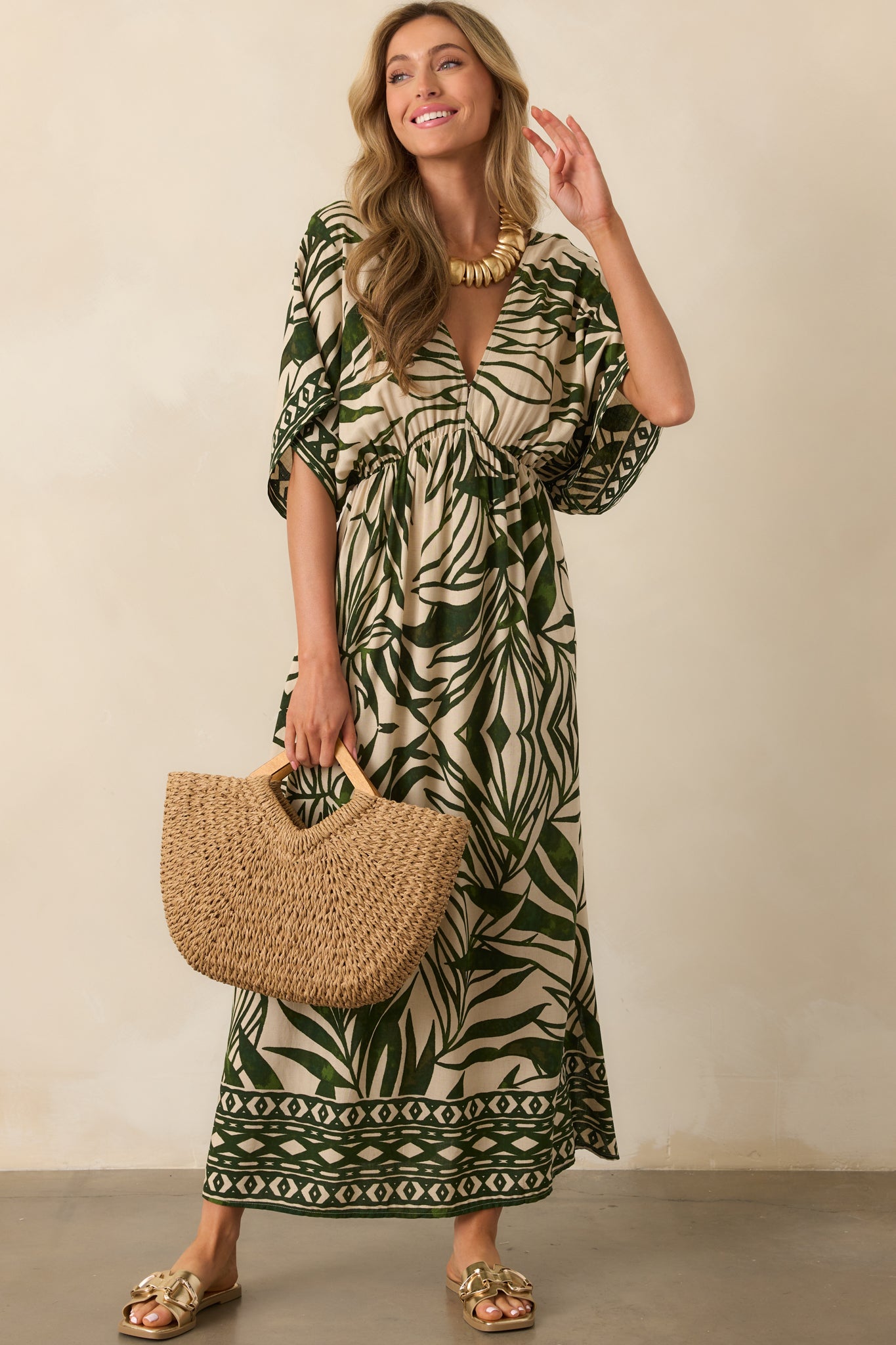 Front view of a green and beige palm leaf print maxi dress, featuring a deep V-neckline, kimono-style short sleeves, and geometric pattern along the hemlines.