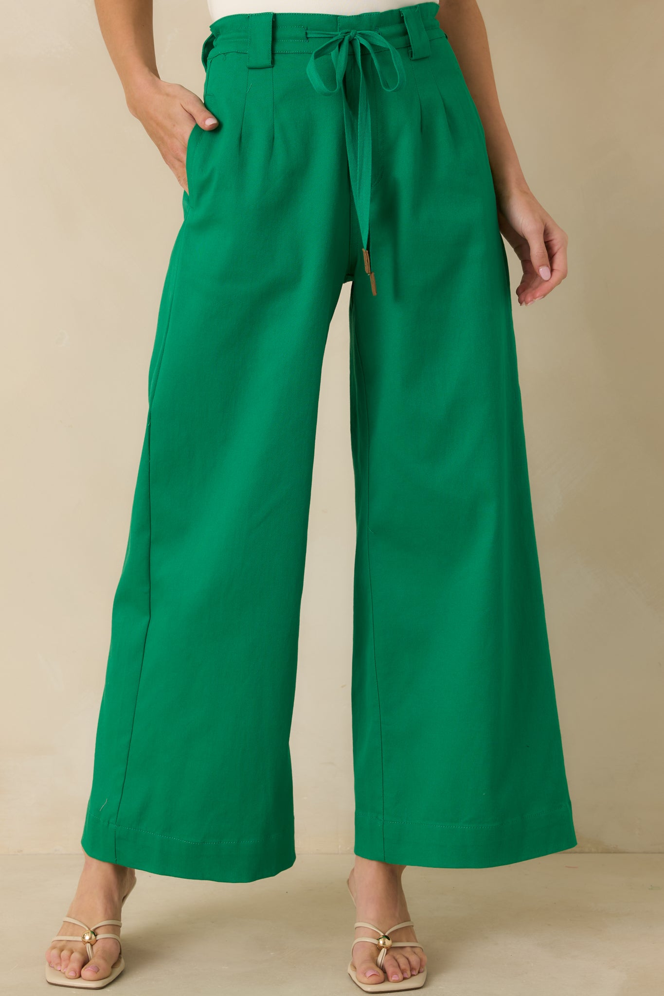 Front view of green pants highlighting the self-tie belt and structured waistband.