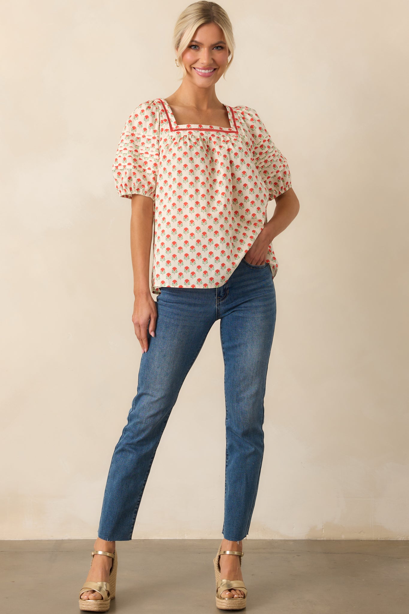 A front view of the cotton top with red floral print, featuring a square neckline with ladder lace trim and short puff sleeves.