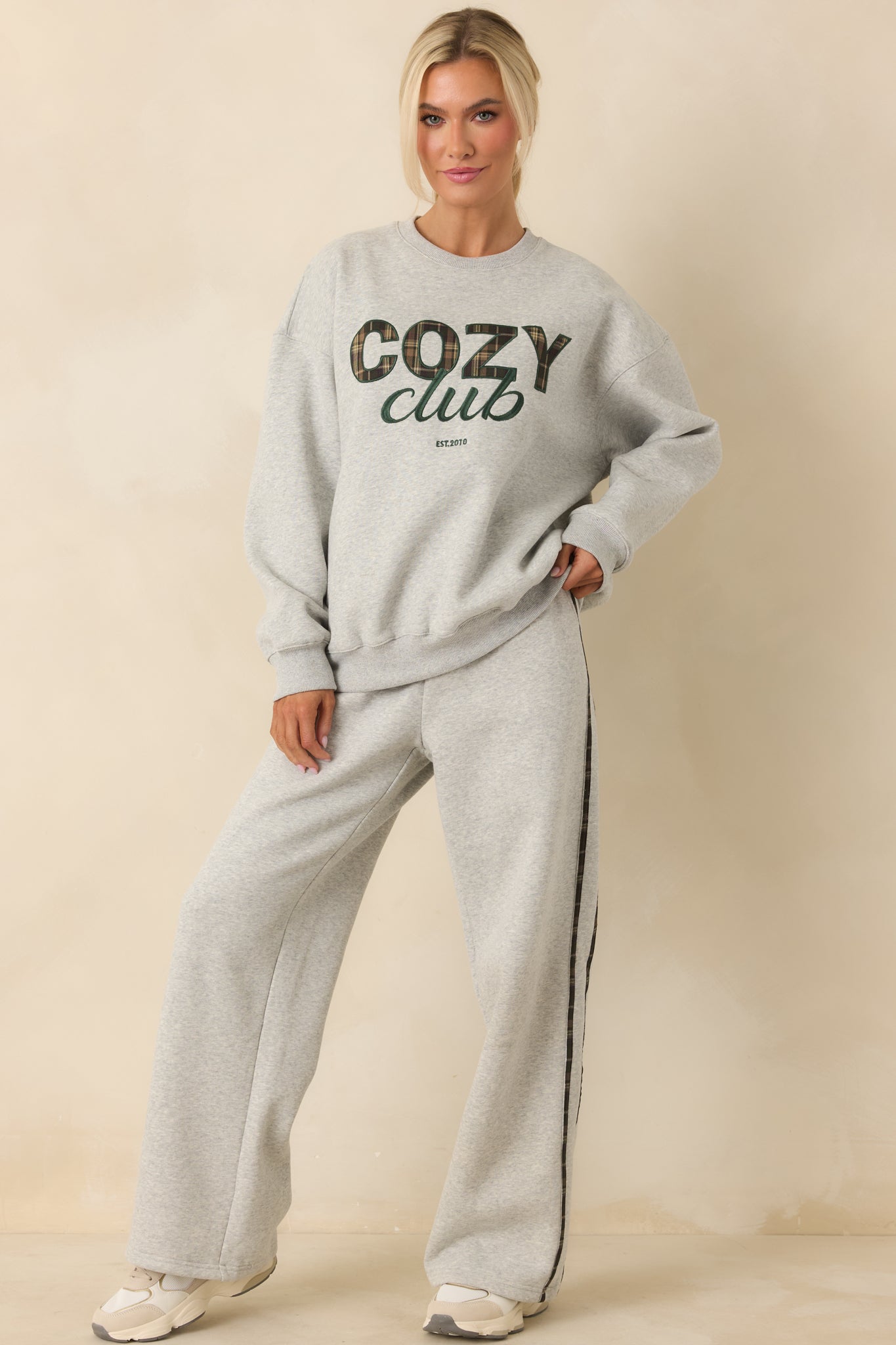 Front view of soft grey sweatshirt featuring ribbed trim and “Cozy Club” plaid graphic.