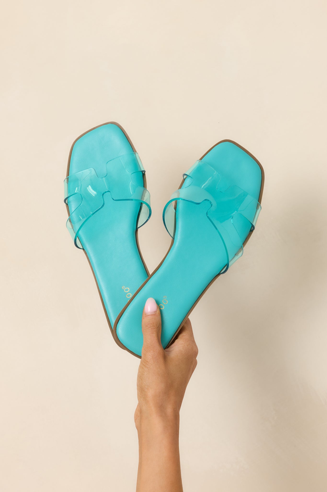 Front view of teal slide sandals displaying open square toe and clear vinyl strap.