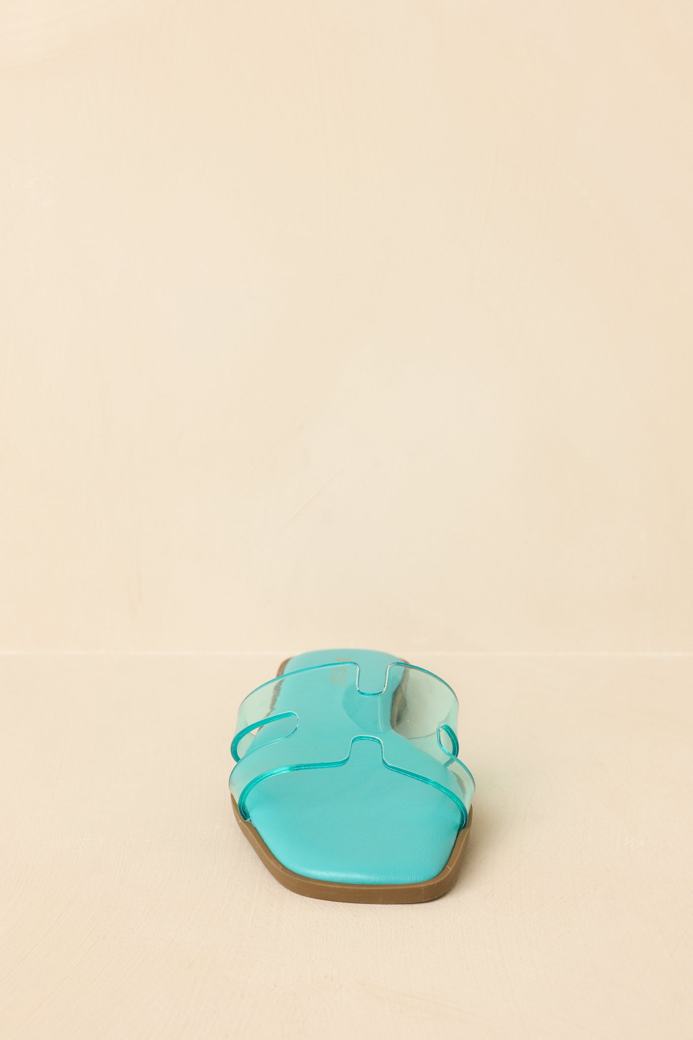 Front view of teal slide sandals displaying open square toe and clear vinyl strap.