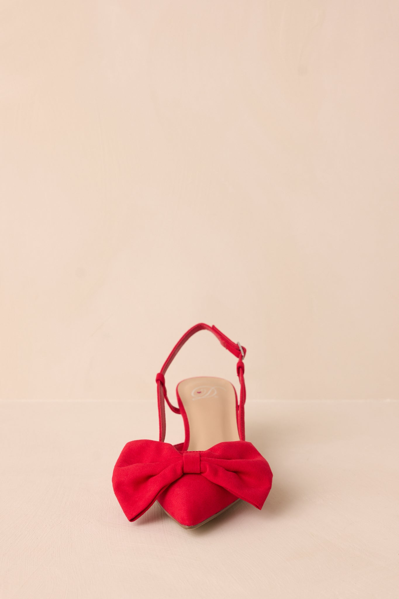 Front view of the red kitten heels, drawing attention to the pointed toes and bold red bow that adorns each shoe.