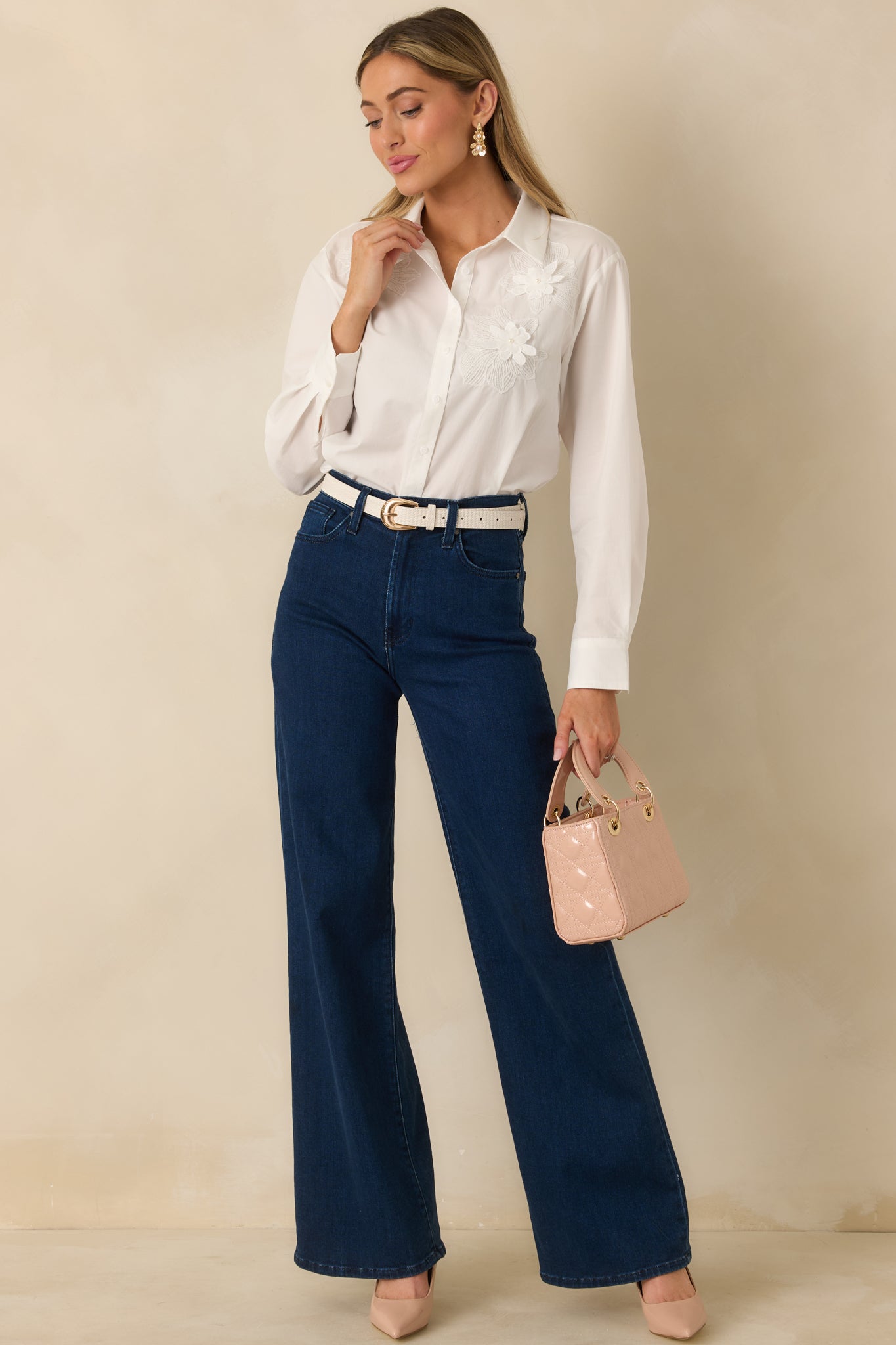 Front view of white button-up blouse with floral appliqué accents, styled with collar open slightly for a casual, airy look.