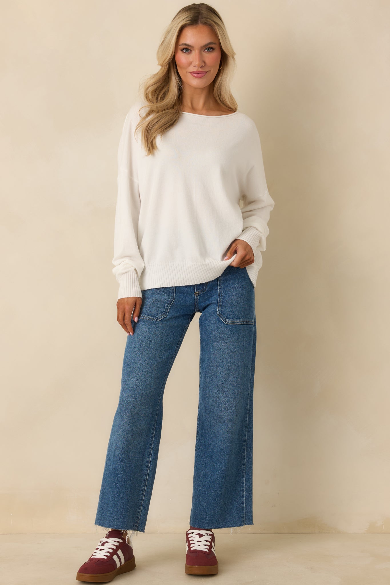 Front view of white knit sweater featuring scoop neckline, long sleeves, and relaxed fit with ribbed hem.