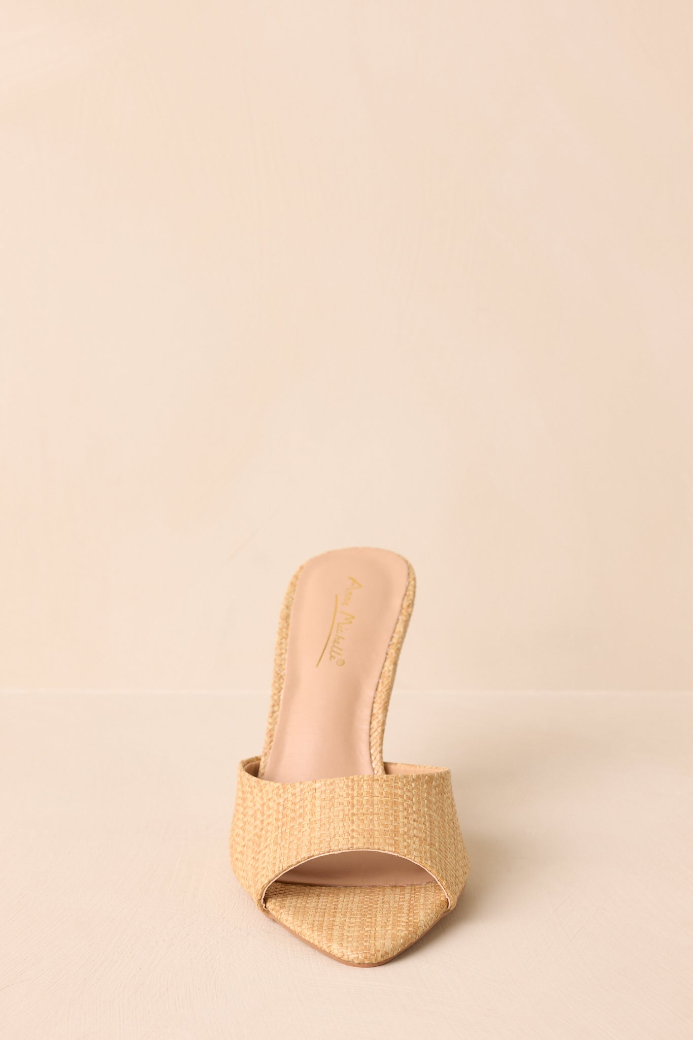 A straight-on front view highlighting the open toe design and woven raffia texture.