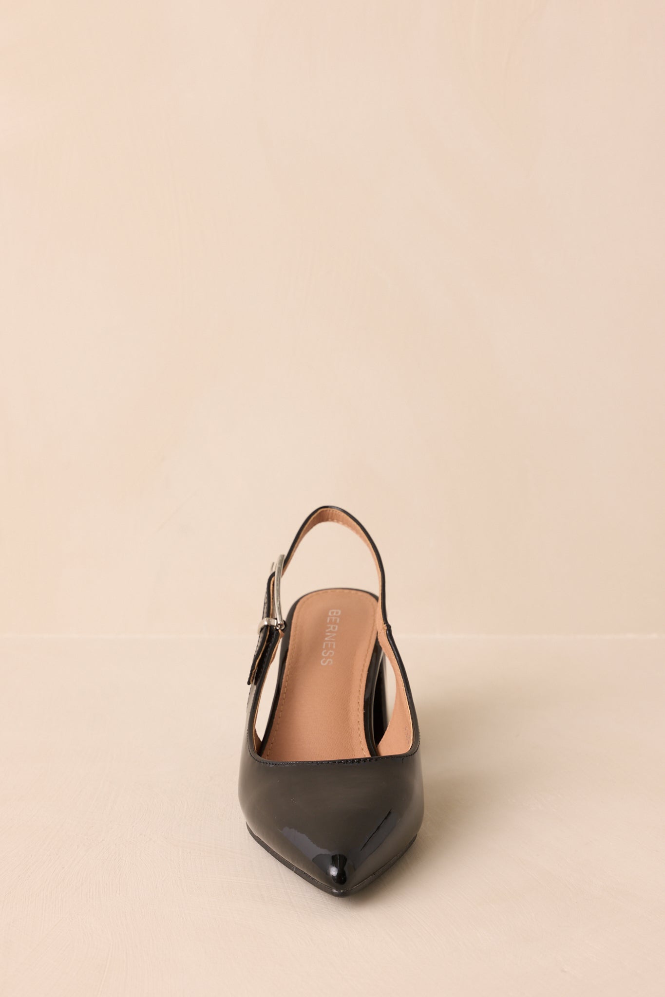 Front view highlighting pointed toe and shiny patent finish.