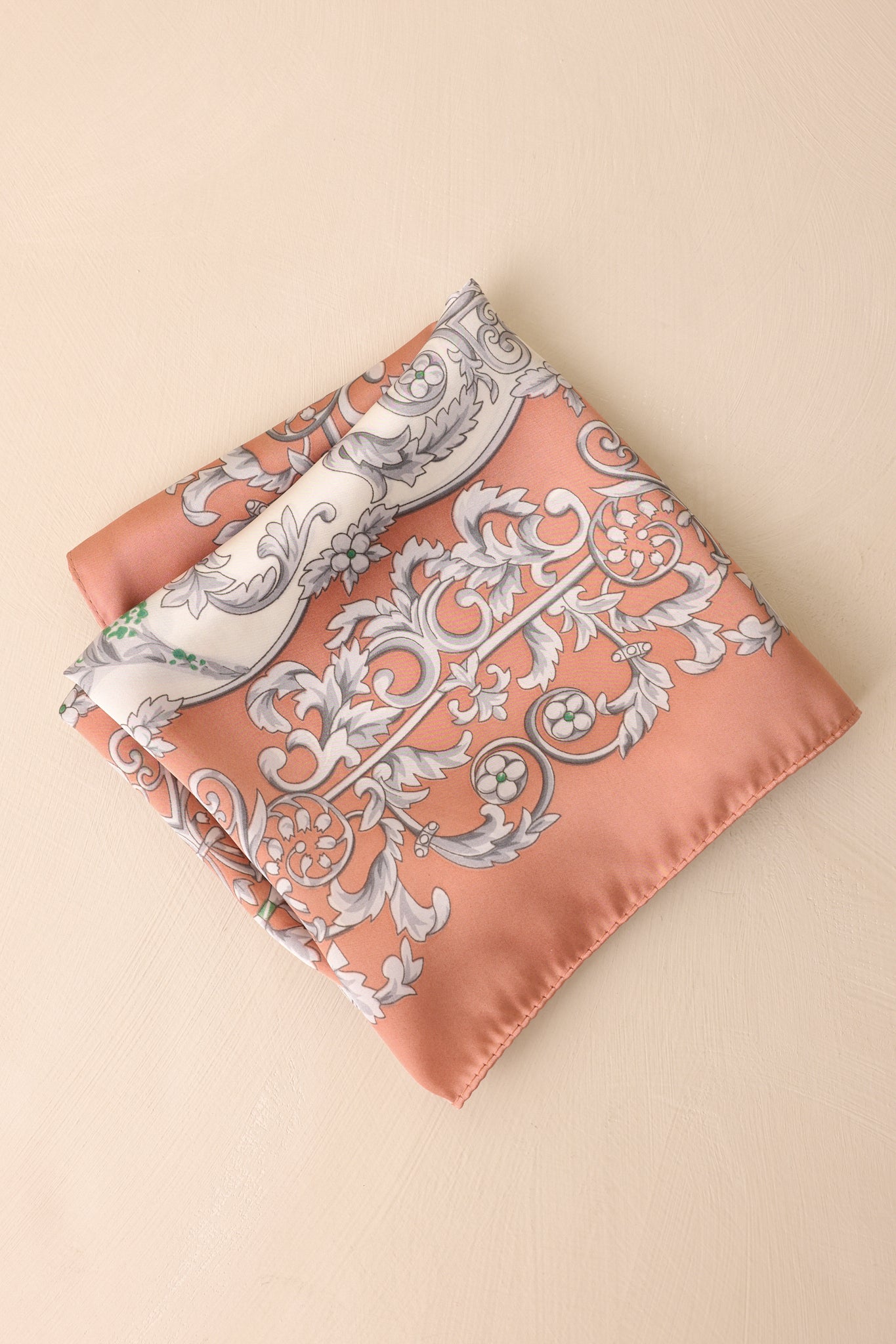 A close-up of the scarf folded, highlighting the intricate grey scrollwork, floral pattern, and smooth satin texture.