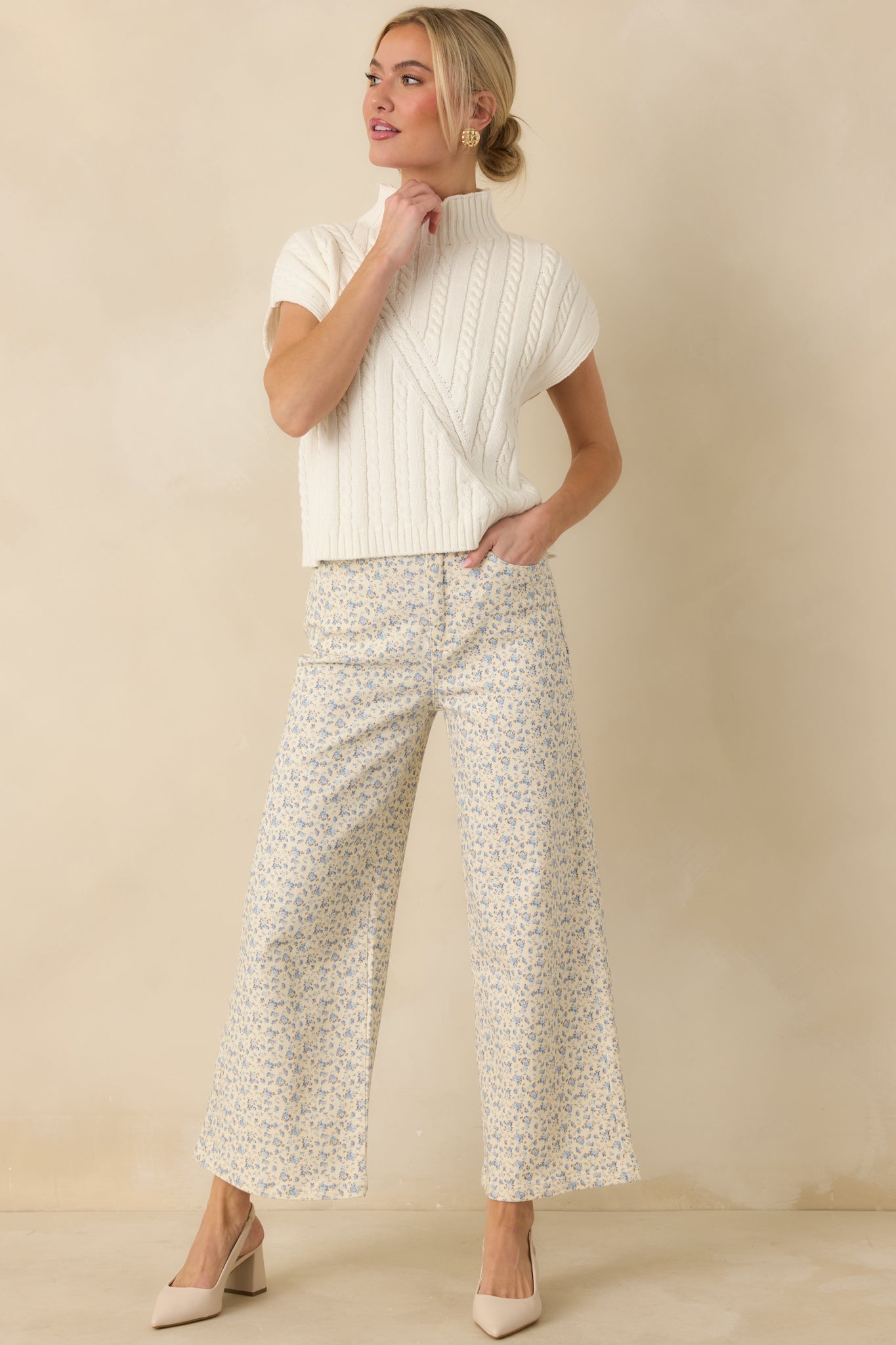 Front view of an ivory sleeveless mock neck sweater showcasing the classic cable-knit texture and relaxed layering silhouette.