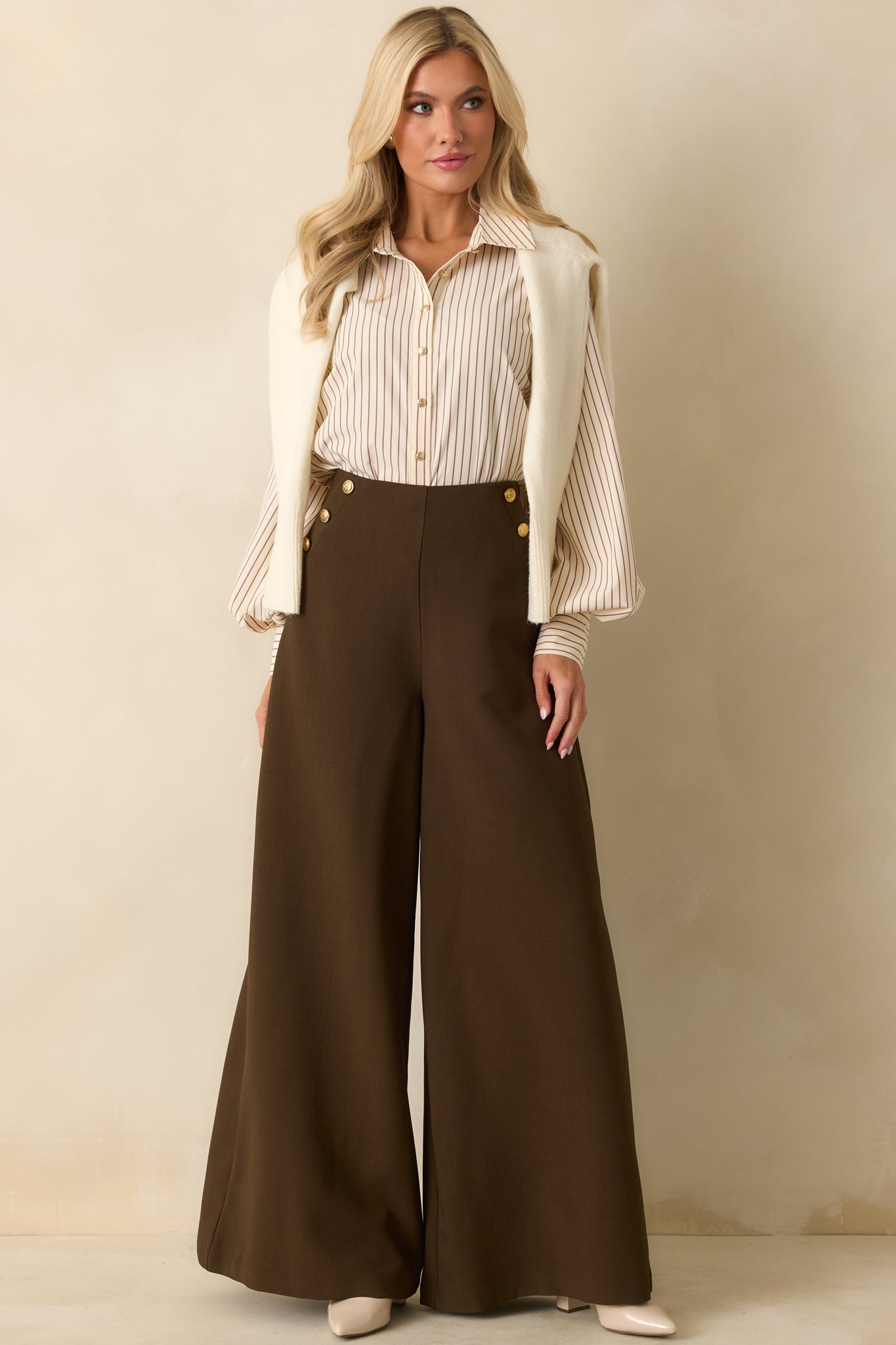 Front view of smooth woven pants featuring embossed gold buttons along the hips.
