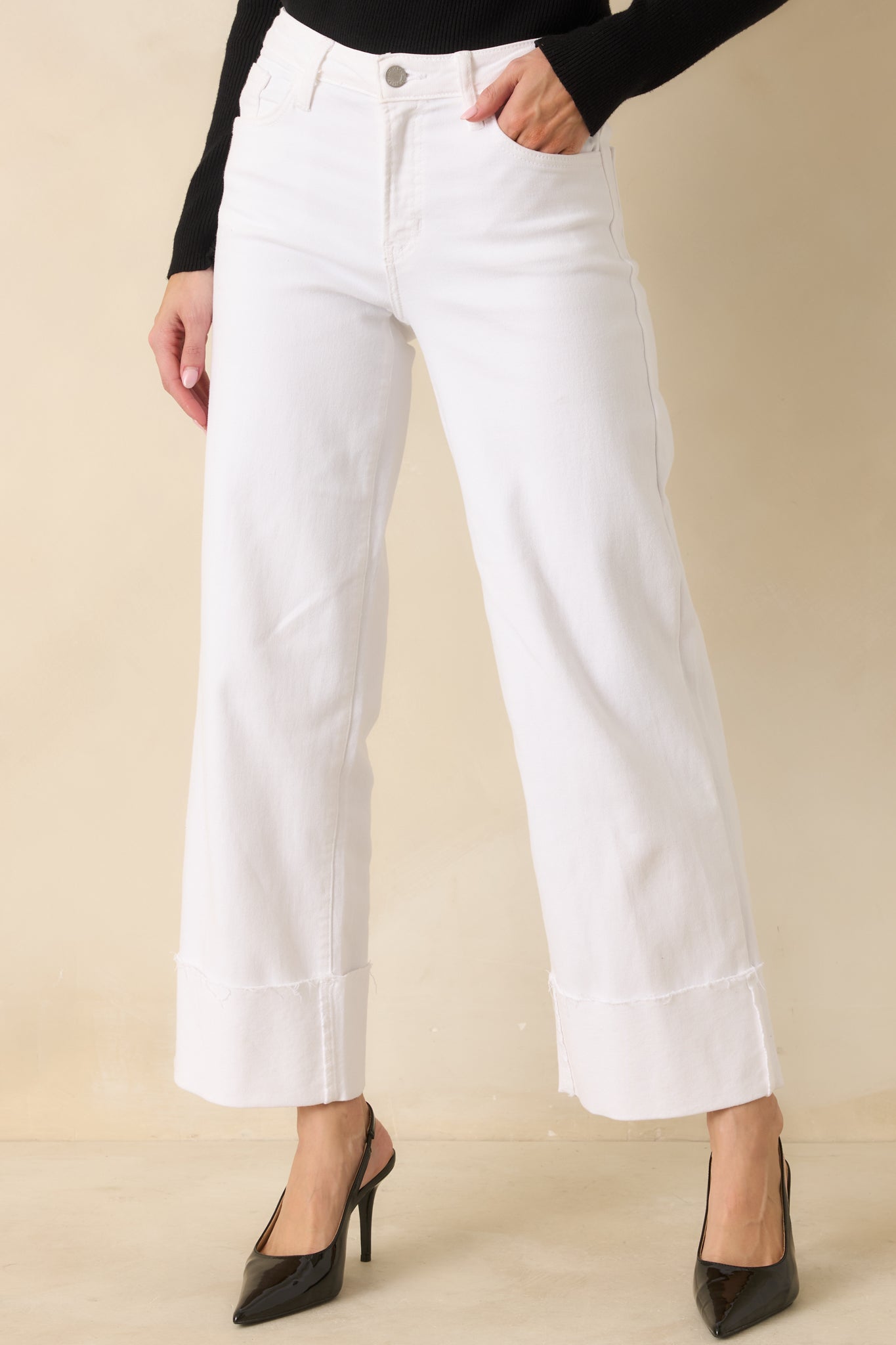 Cropped front view of the white jeans focusing on the high-rise waistband, belt loops, and button and zipper closure.