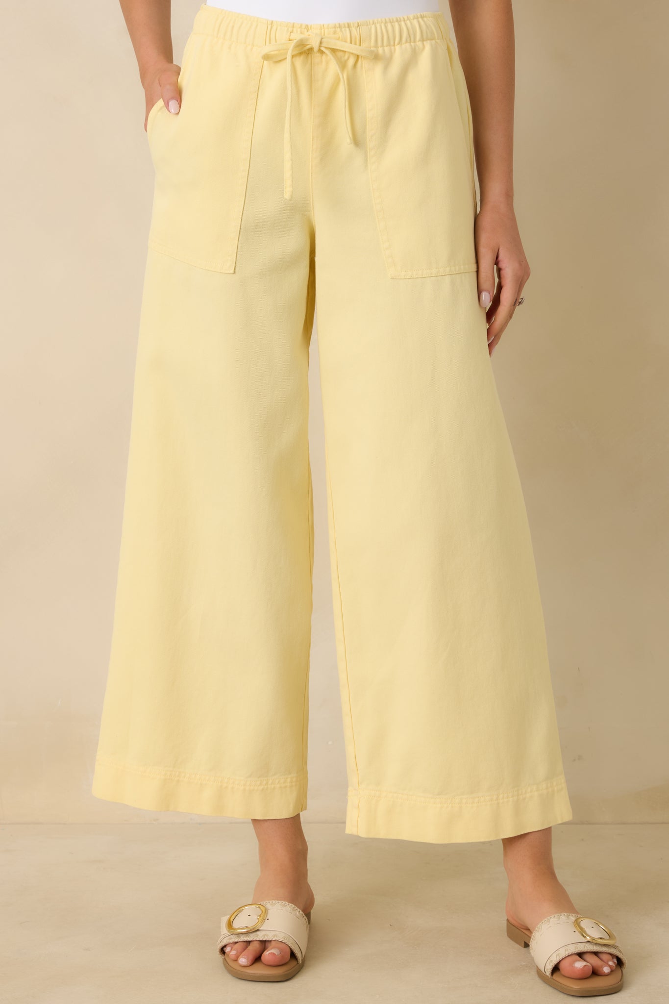 Front cropped view of the yellow wide-leg pants highlighting the adjustable drawstring and soft elastic waistband.