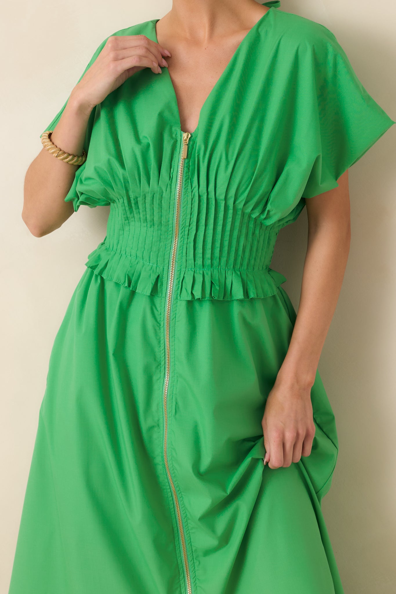 Close-up of the front zip closure, smocked waistband, and ruffled trim details.