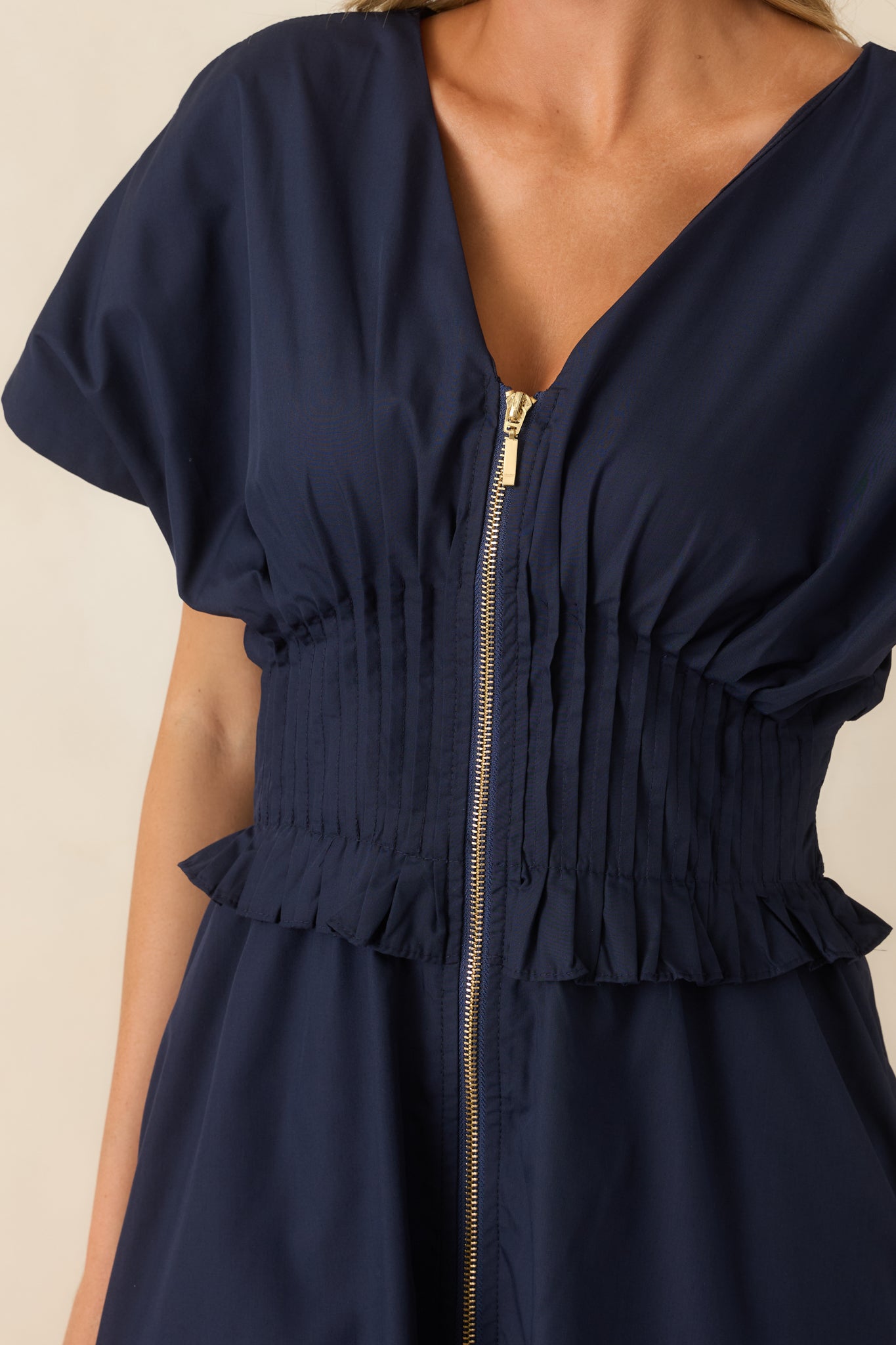 Close-up of the front zip closure, smocked waistband, and ruffled trim detailing.