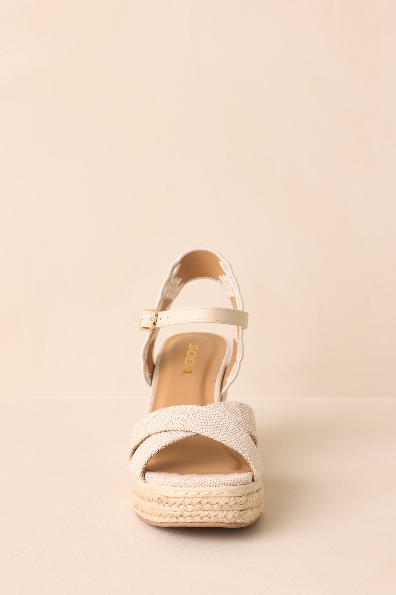 A detailed frontal view of the wedge heels, displaying the open toe and crossing canvas straps.