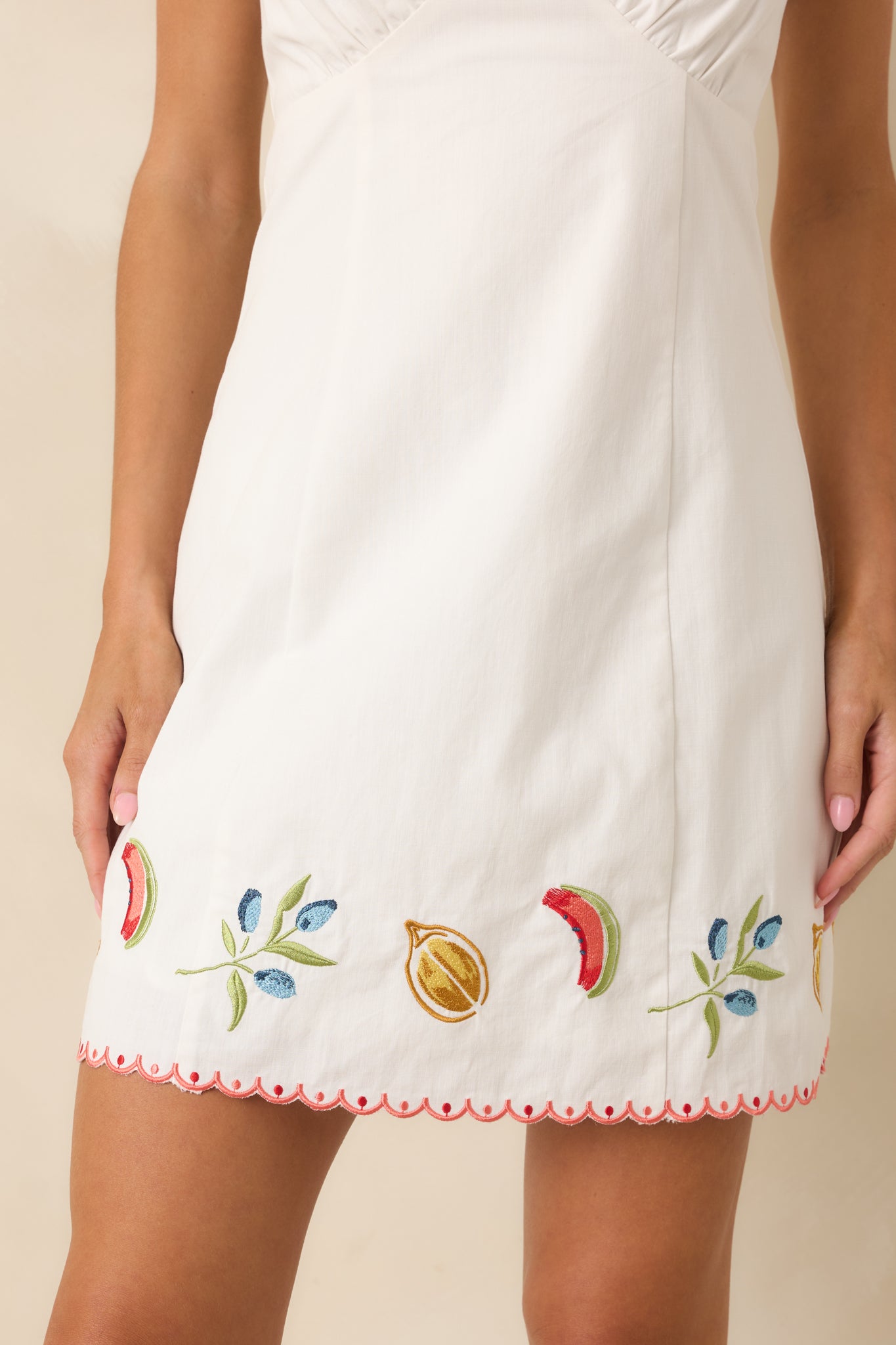 Close-up of colorful fruit embroidery, scalloped trim, and textured cotton fabric details.