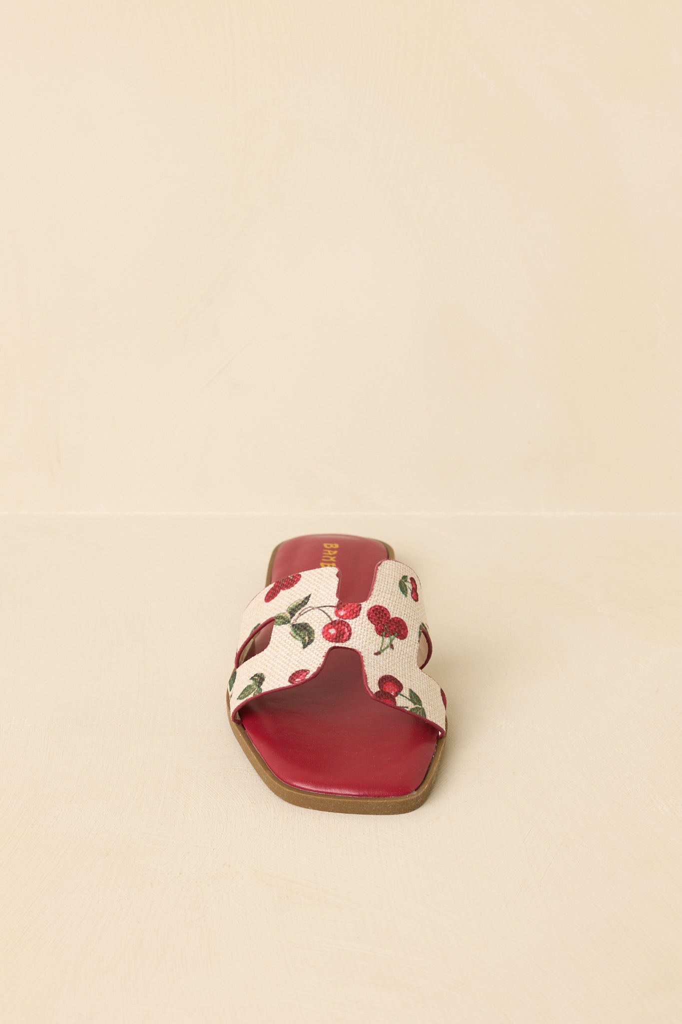 Fruit print slide sandals displayed on a beige background, showcasing wide strap and open-toe design