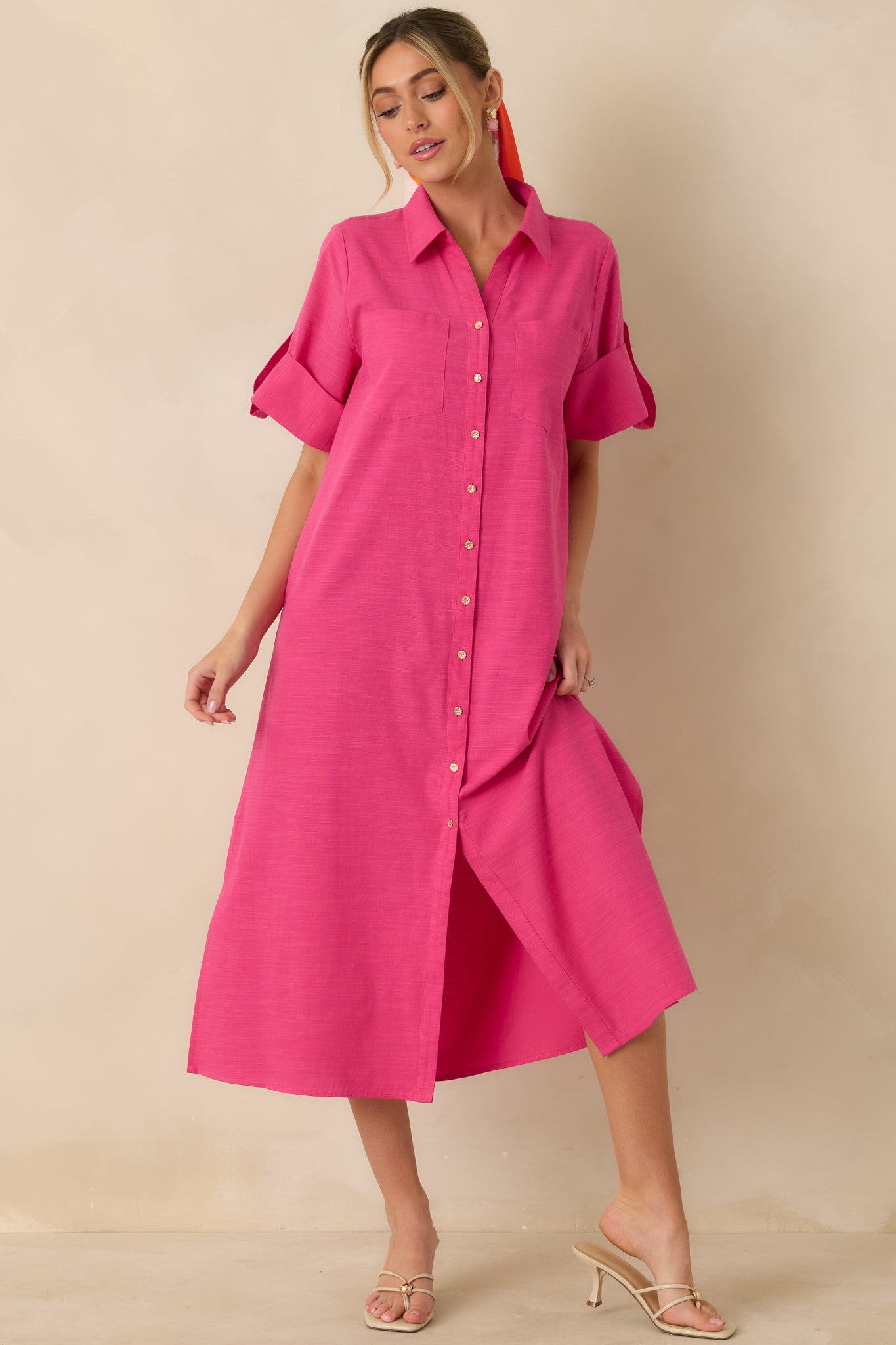 Fuchsia cotton midi shirt dress showcasing a collared neckline, full-length gold-tone button closure, and long sleeves that can be rolled or worn down.