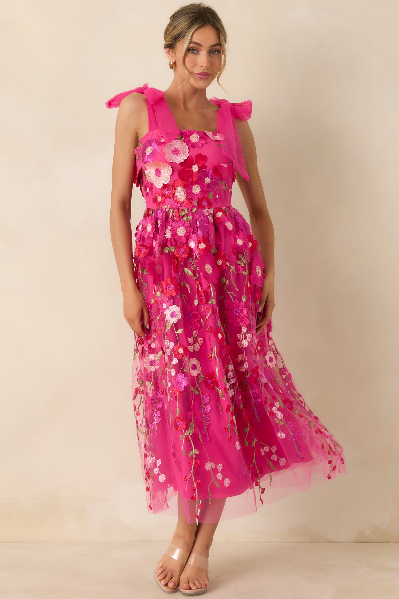 Front-facing full body image emphasizing the embroidered floral detailing and flowing silhouette of the fuchsia dress.