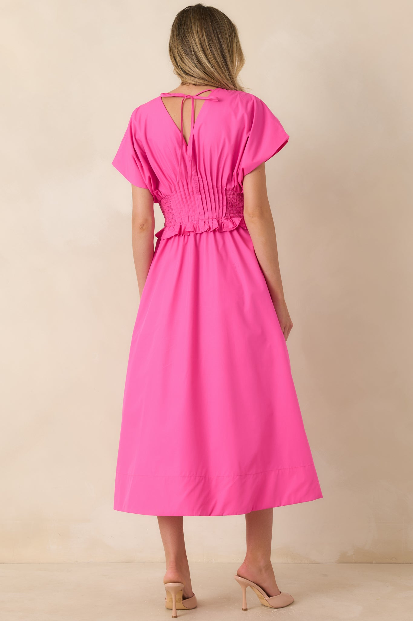Back view of the fuchsia maxi dress highlighting the smocked waistband and flowing A-line silhouette.