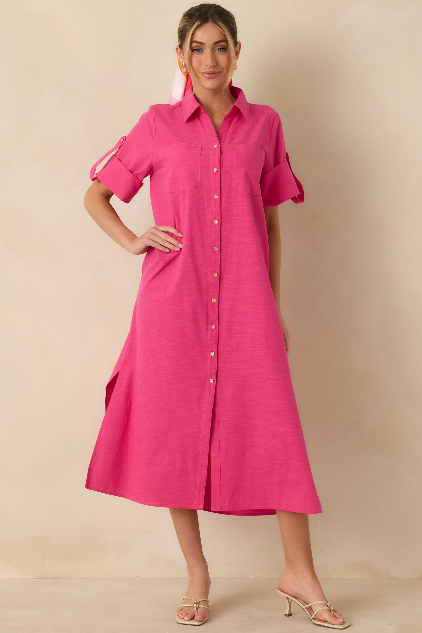 Midi-length fuchsia shirt dress with lightweight cotton fabric, relaxed straight fit, collared neckline, and long sleeves with a full gold-tone button-front design.