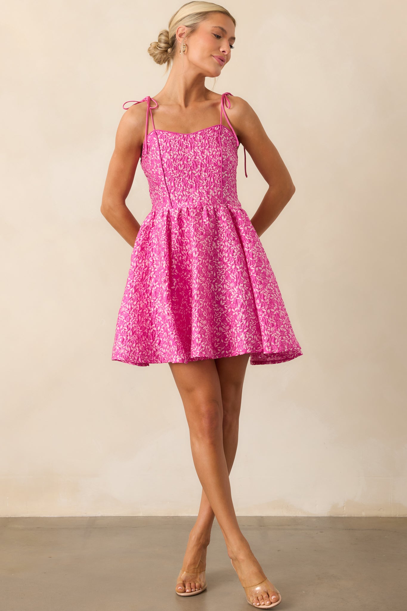 Fuchsia pink mini dress with a floral print, shown in a full view highlighting its flared hem and structured sweetheart neckline.