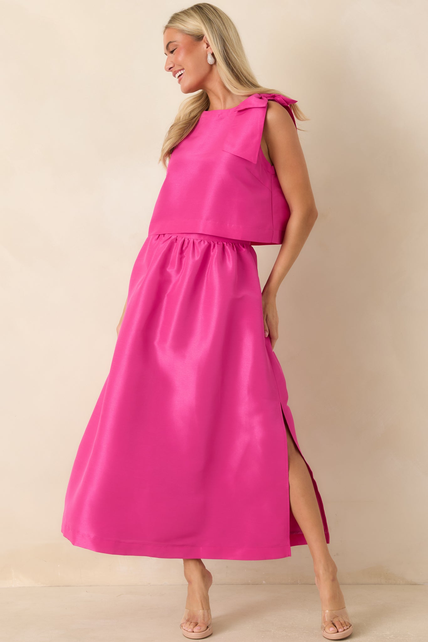 Fuchsia sleeveless top featuring a high neckline, statement shoulder bow, and relaxed boxy silhouette.

