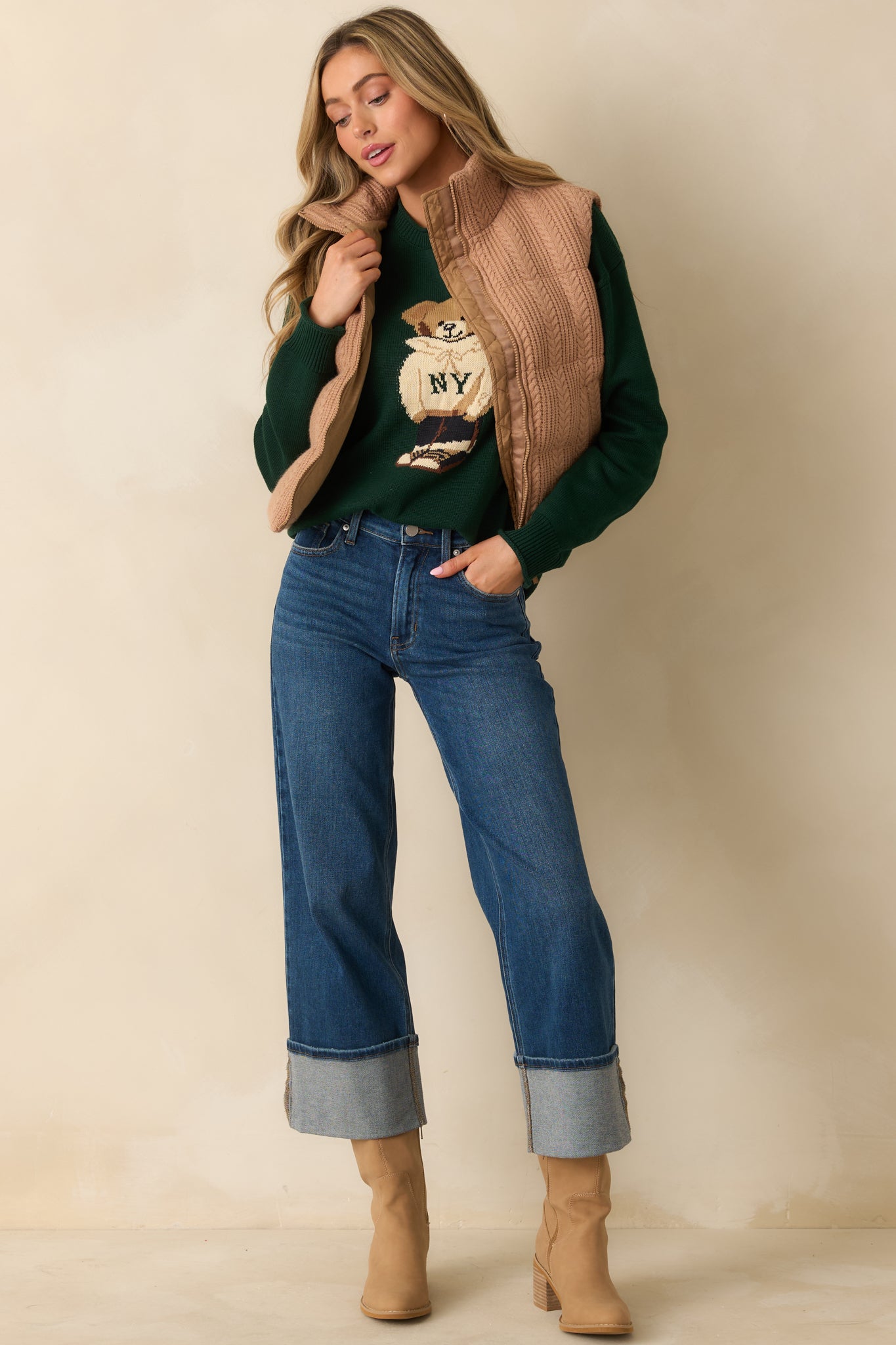 Full body of model wearing brown puffer vest with quilted cable knit exterior and high stand collar.