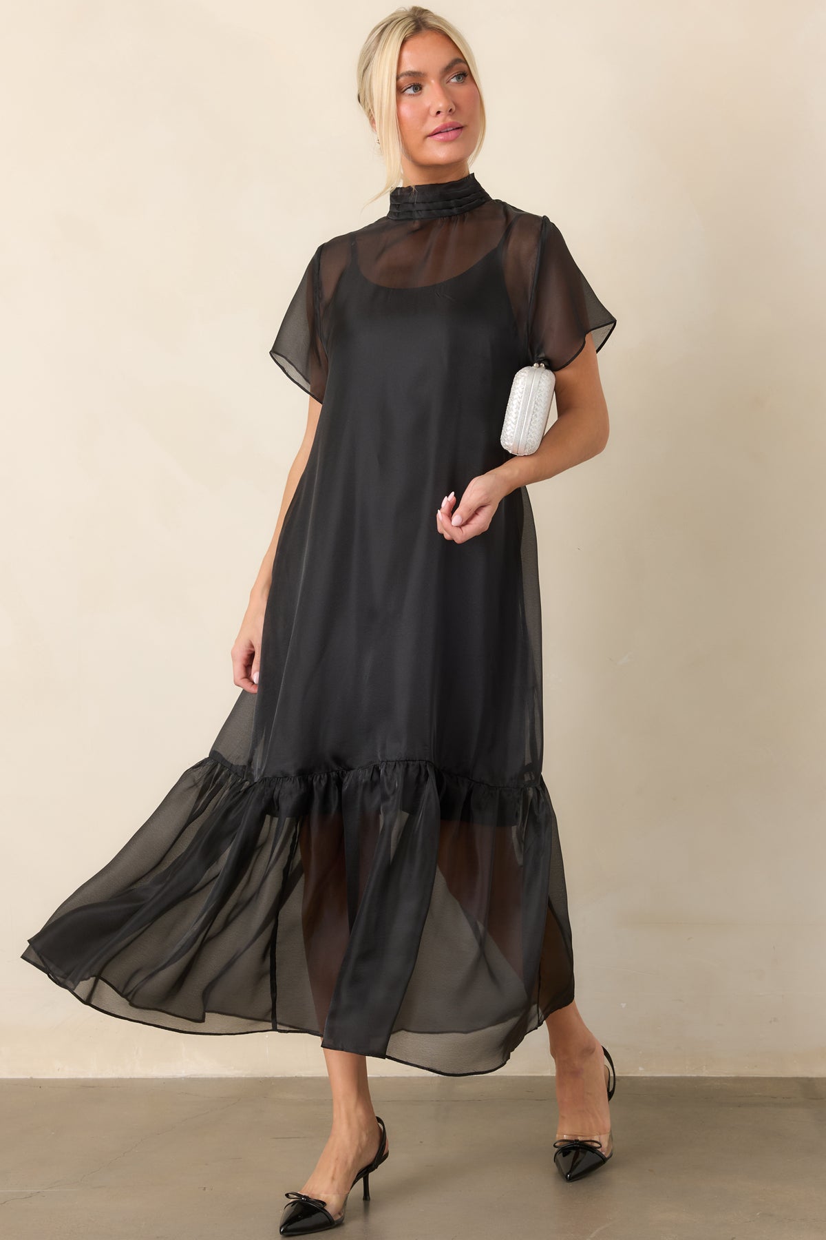 Full body featuring kitten heels with pointed toes, delicate bow accents, clear side panels, and styled with a black event dress.