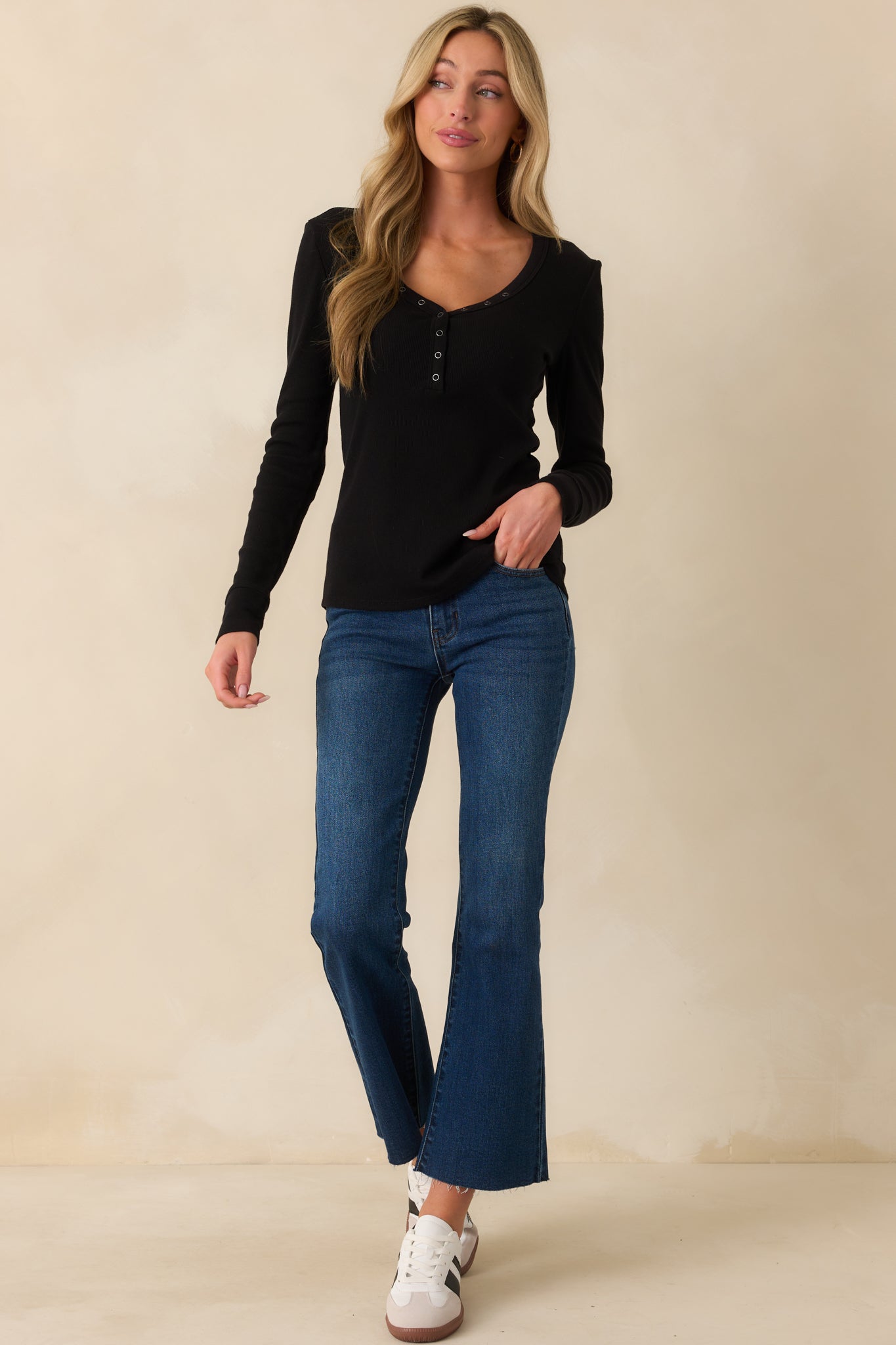 Full body front view of the black top showing the henley v-neckline with functional snap buttons and long sleeves.