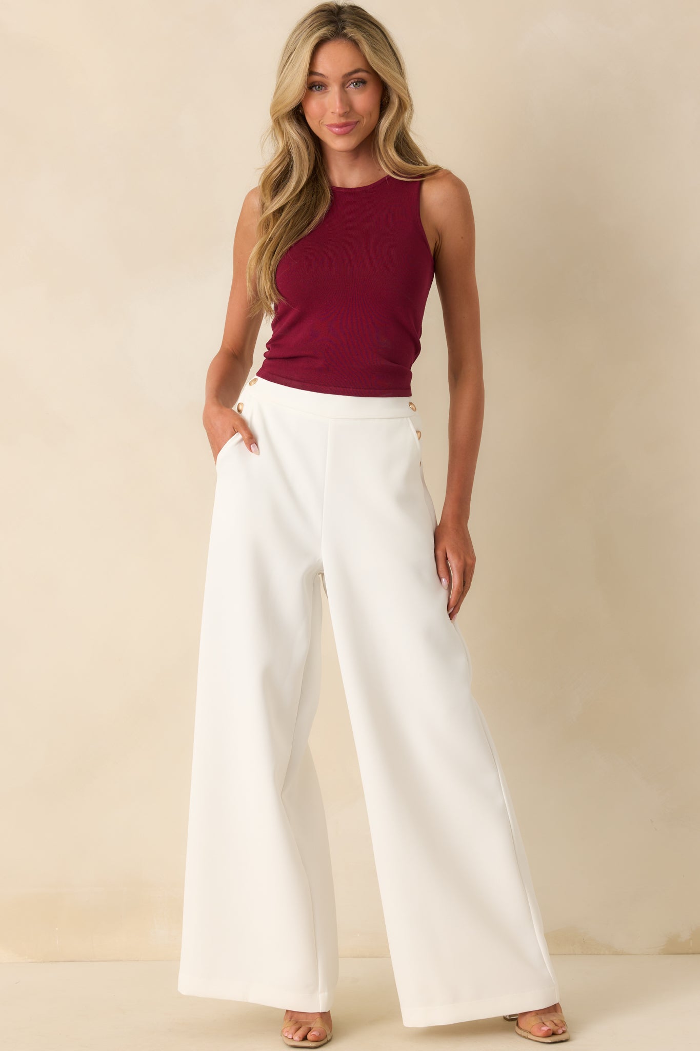 Full body shot emphasizing the high waist and clean lines of the pants with gold button detailing.