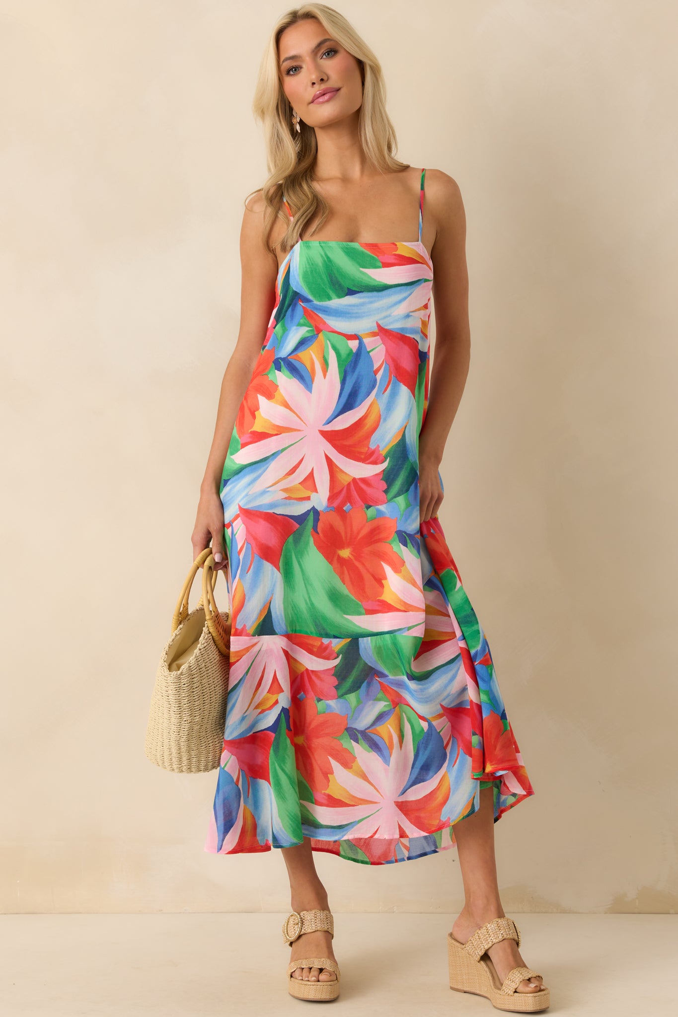 Angled full body image showing the airy drape of the dress and the vivid tropical floral print from top to hem.