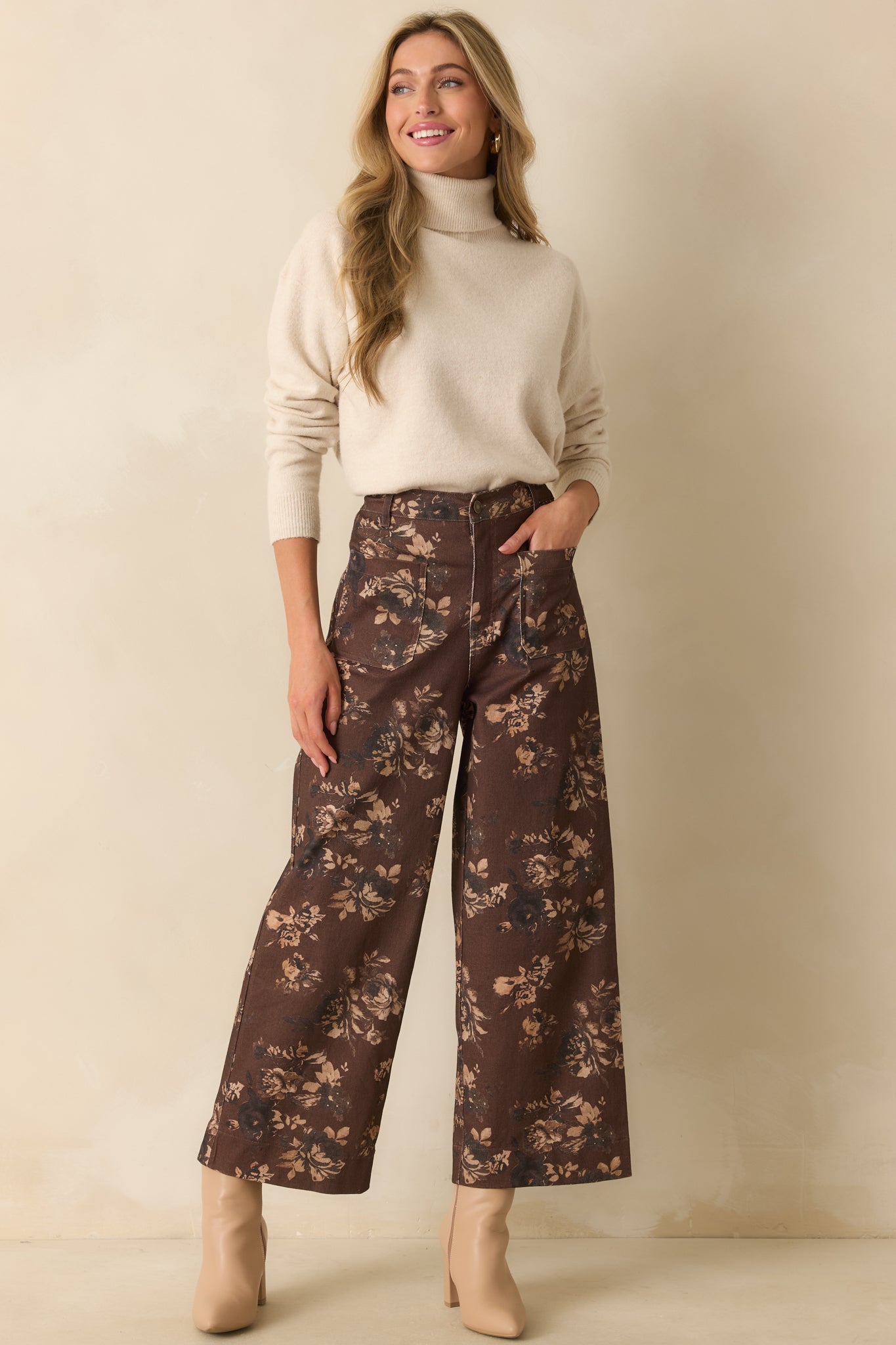 Full body photo showing the light beige sweater with a fold-over turtleneck collar and relaxed fit.