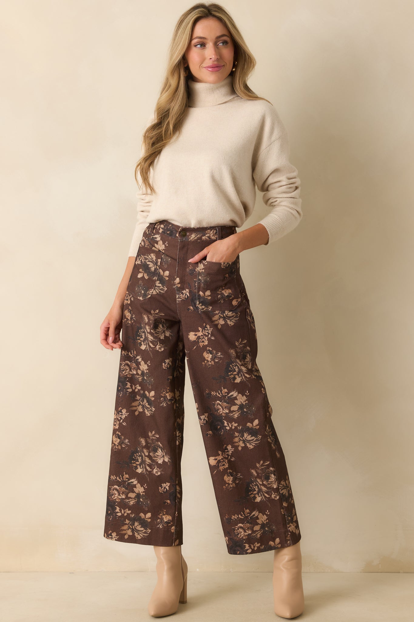 Full body photo highlighting the long-sleeve light beige turtleneck sweater with ribbed knit trim at the cuffs and hem.