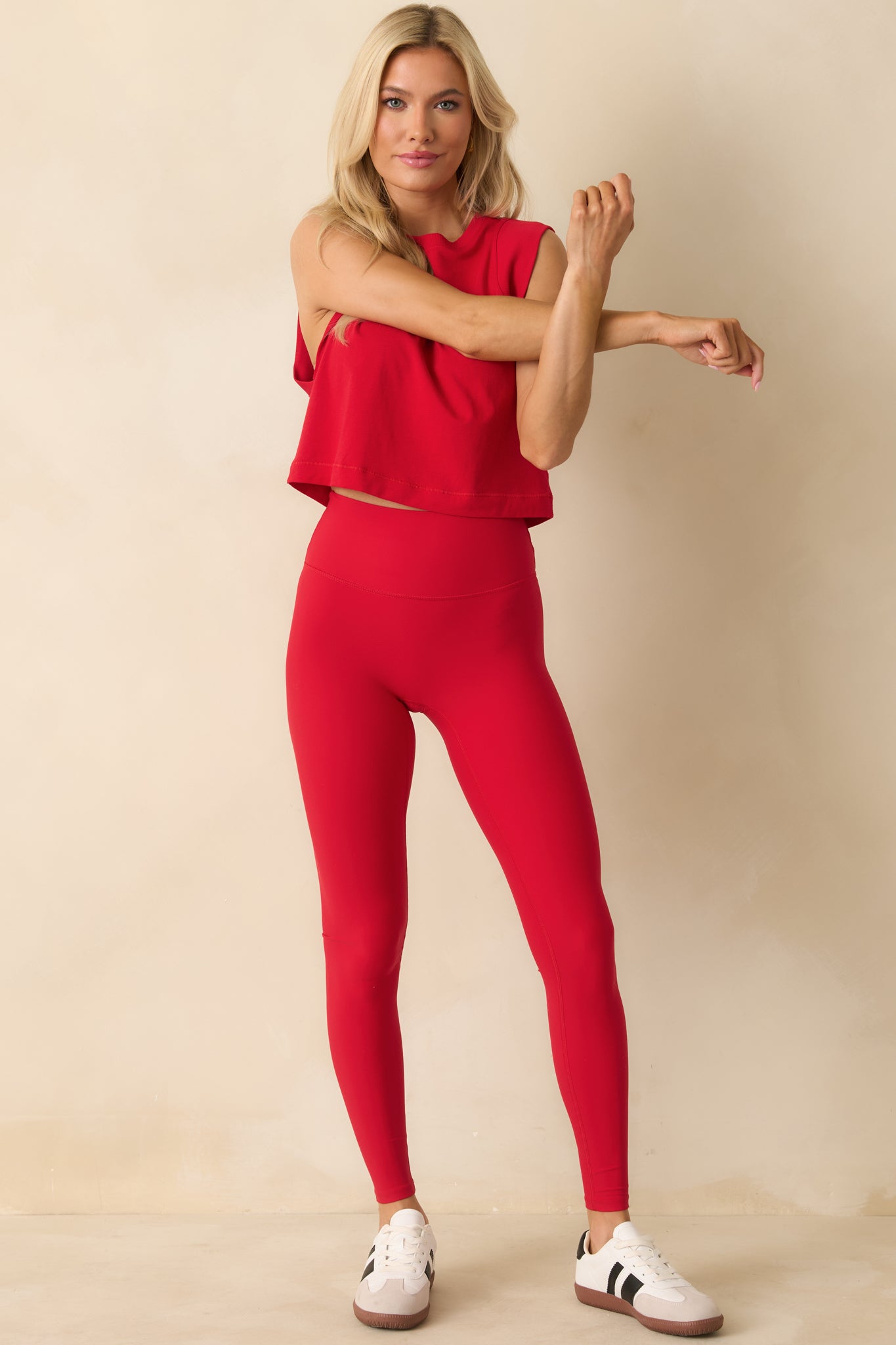 Full body photo of model wearing a red sleeveless crew neck cropped tank top with a relaxed fit.