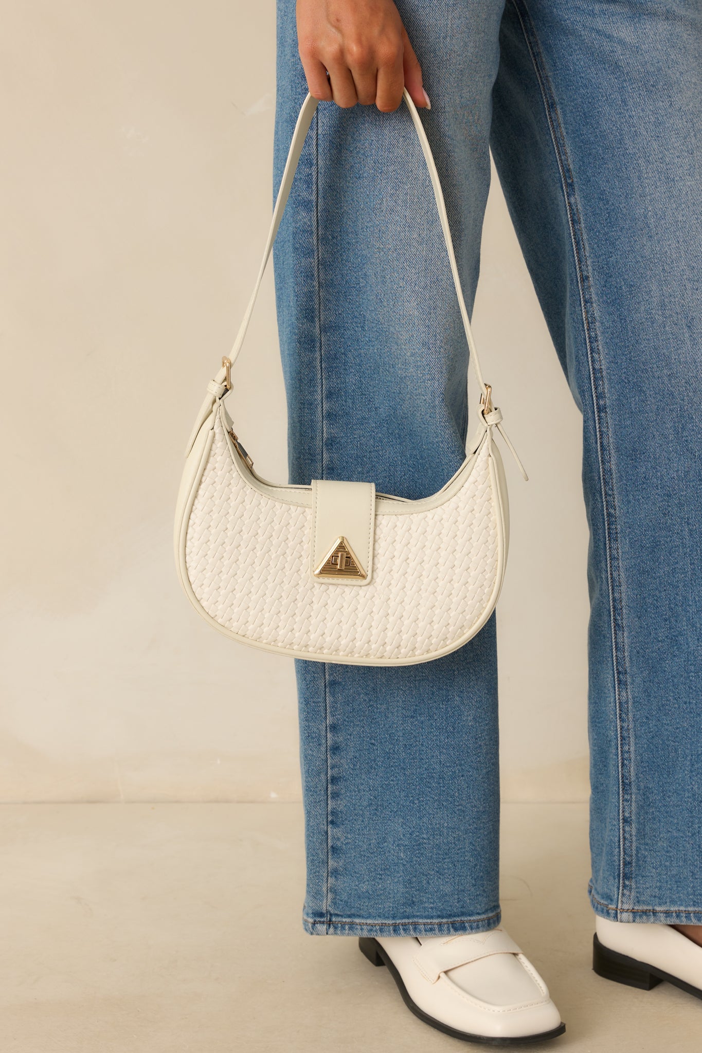 A full body angled view showing the adjustable strap and structured base of the white shoulder bag.
