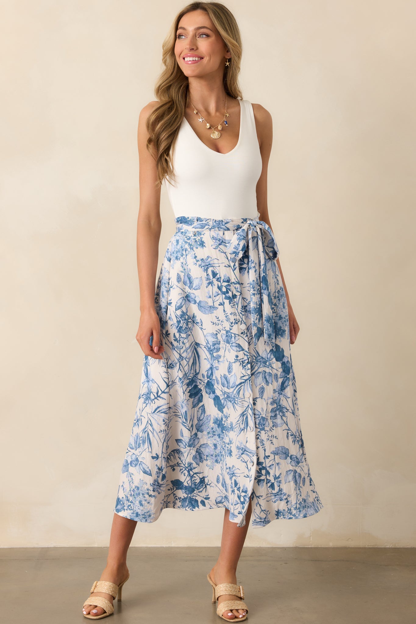 Head-to-toe image highlighting the functional button front of the blue floral skirt and its breezy drape.