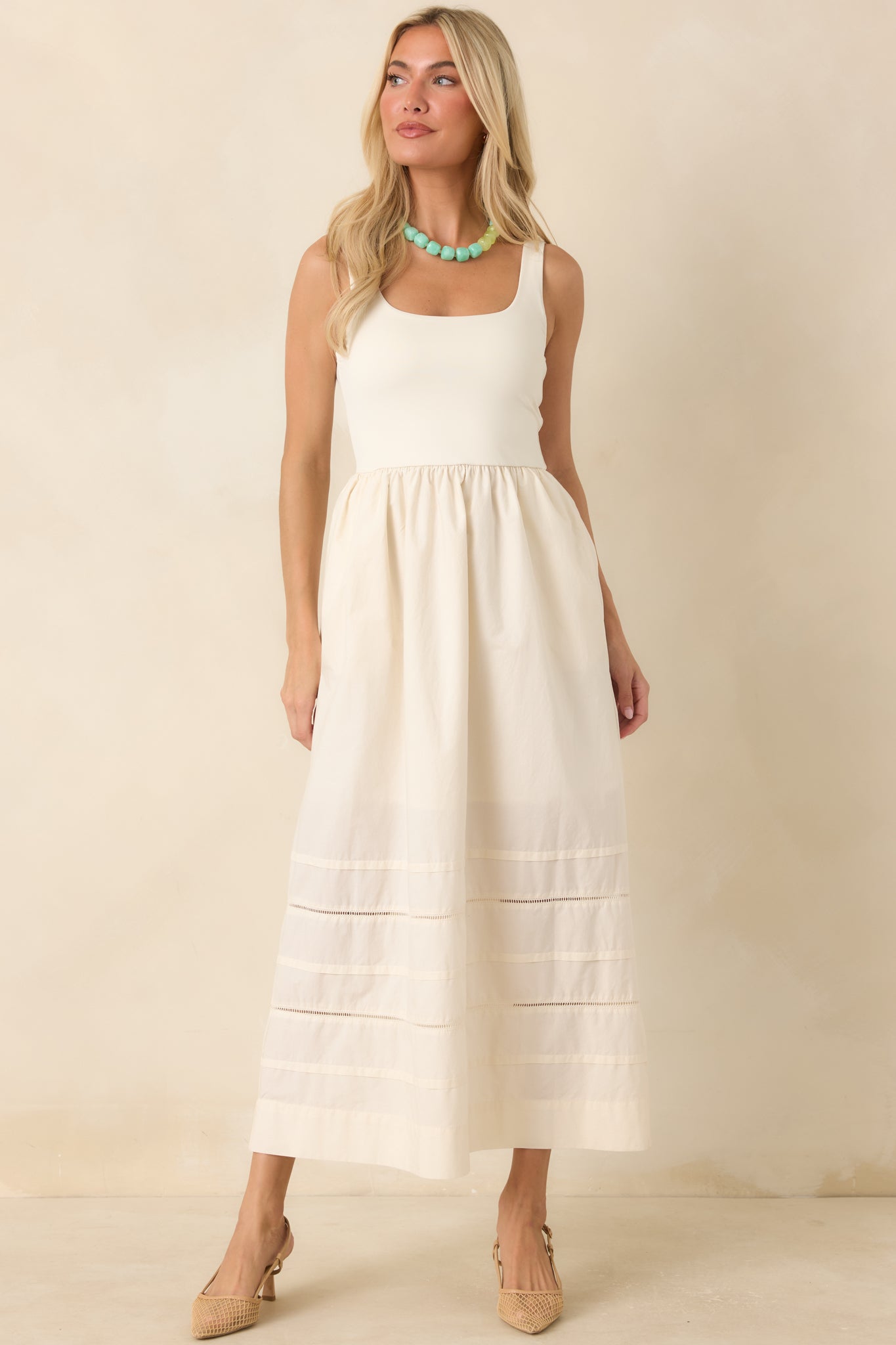 Full body view of white maxi dress with a fitted, stretchy bodice and sleeveless silhouette. Featuring subtle horizontal inset panels near the hem add texture and dimension to this timeless design.
