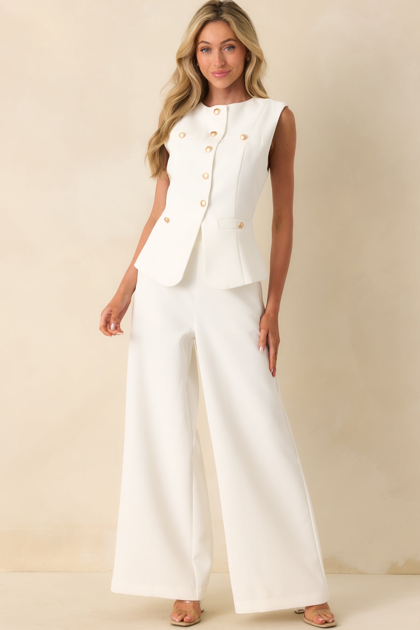 Full body front view of the white wide-leg pants featuring a thick waistband and four gold buttons on each side.
