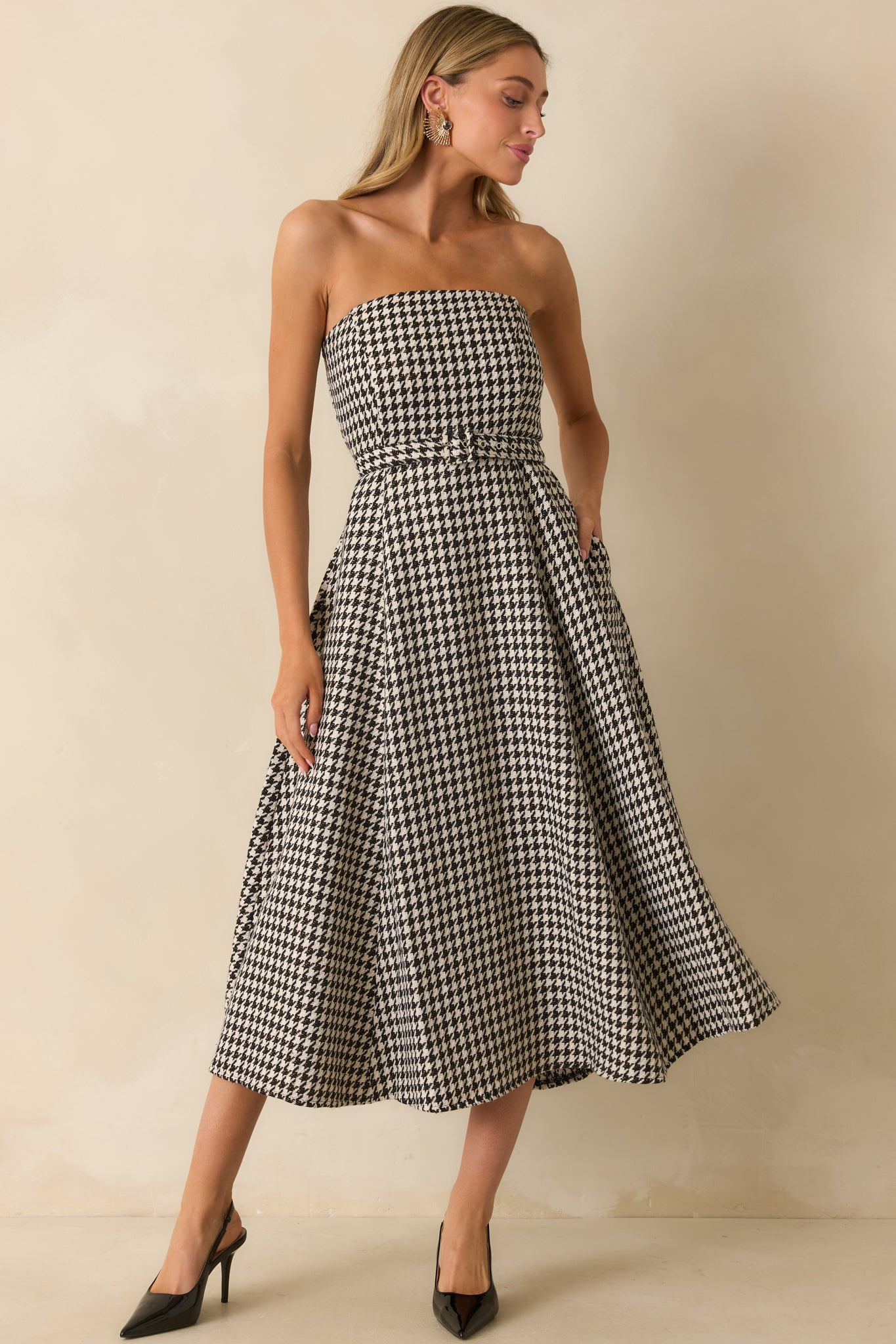 Full front view showing the black houndstooth bandeau midi dress with strapless neckline and belted waist.