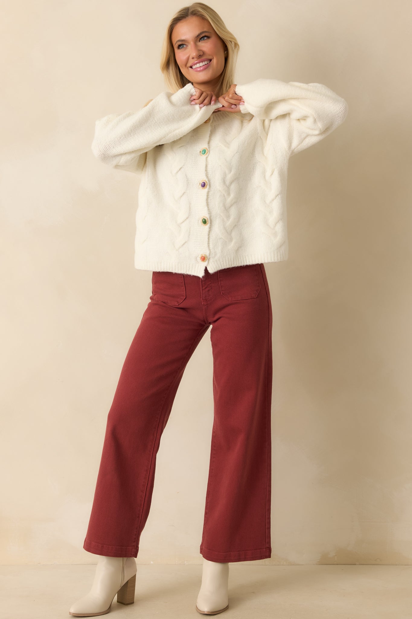 Full-length front view of ivory cable knit cardigan featuring long sleeves, relaxed fit, ribbed trim, and colorful buttons.
